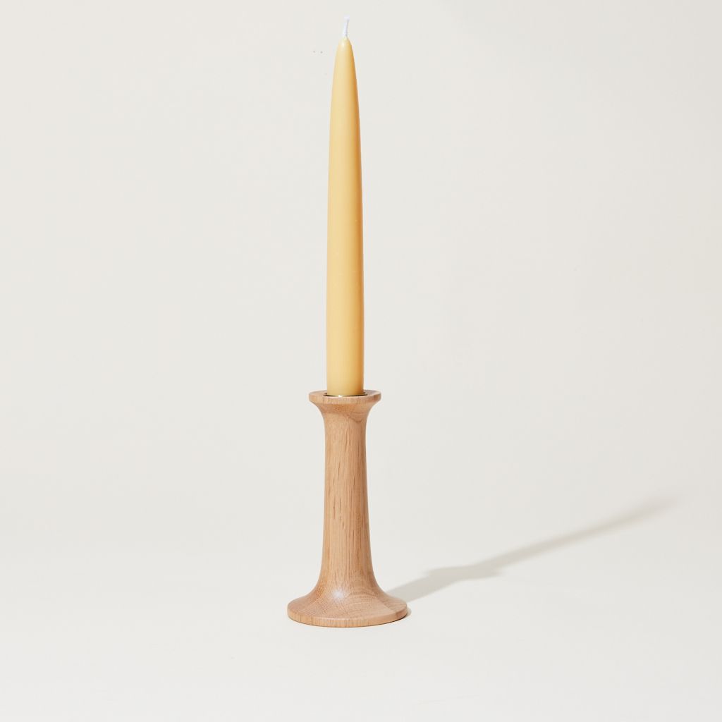 Thin light wood cylinder with a slightly wide base with a taper candle sitting on top