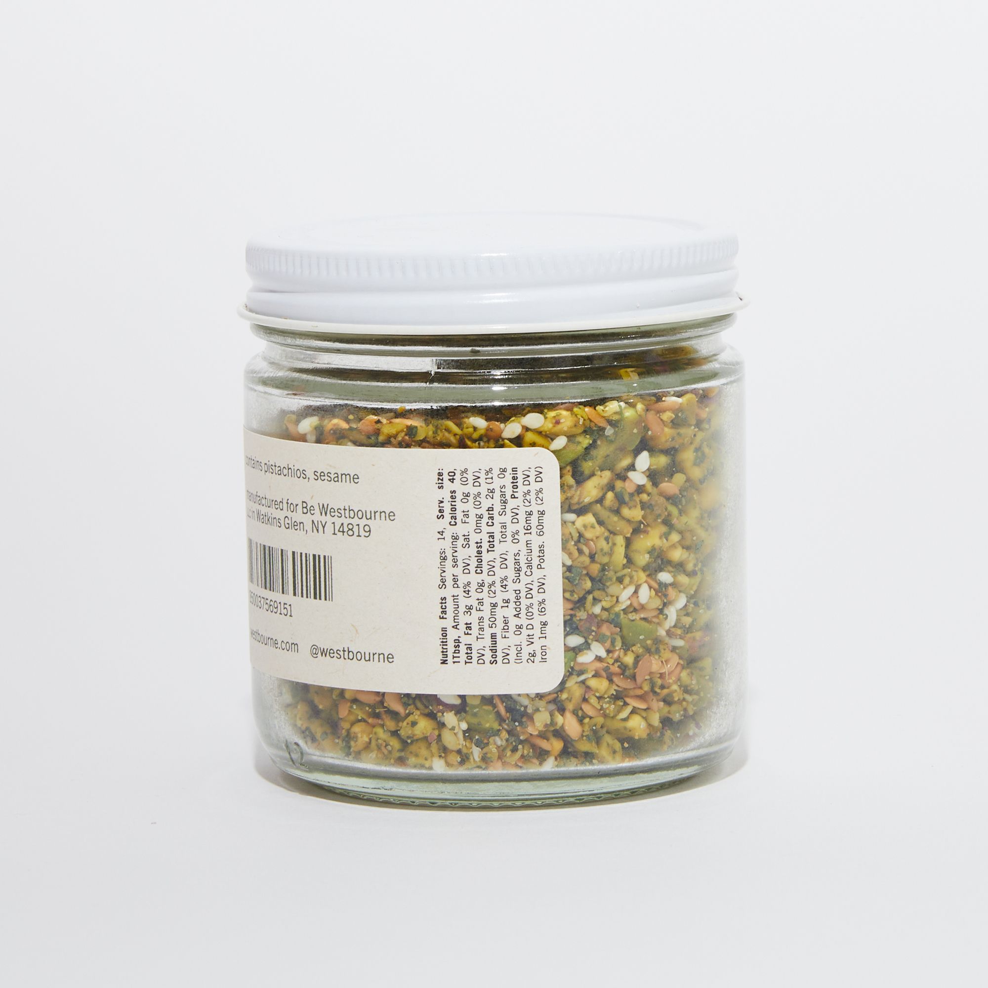 Clear jar of pistachio dukkah with a white lid featuring nutritional facts