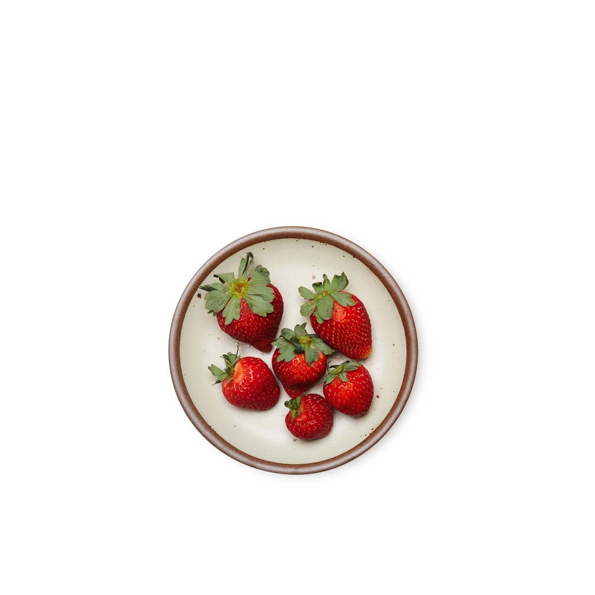 Strawberries on a dessert sized ceramic plate in a warm, tan-toned, off-white color featuring iron speckles and an unglazed rim.