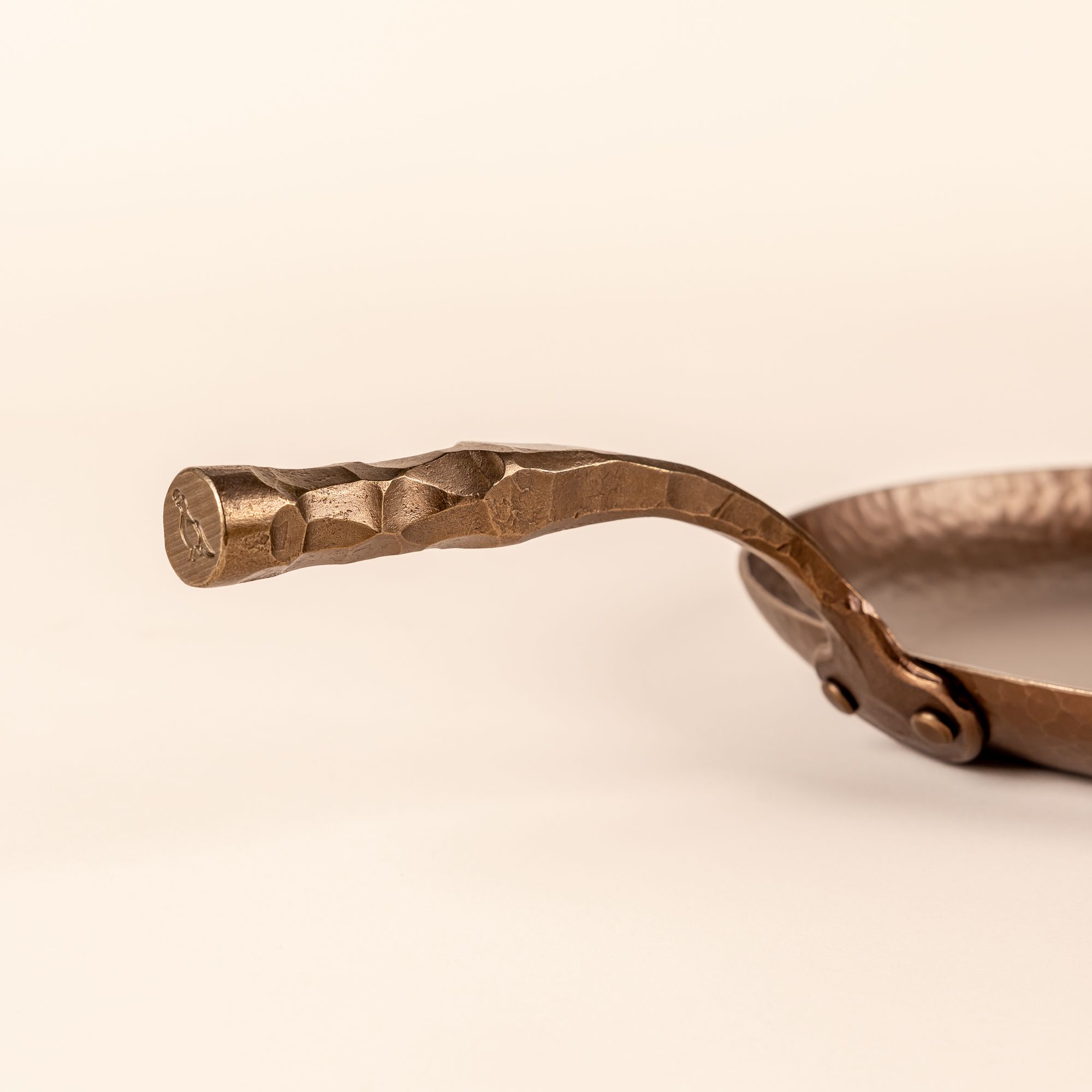 The handle of a carbon steel farmhouse skillet with a hammered texture and hand forged design.