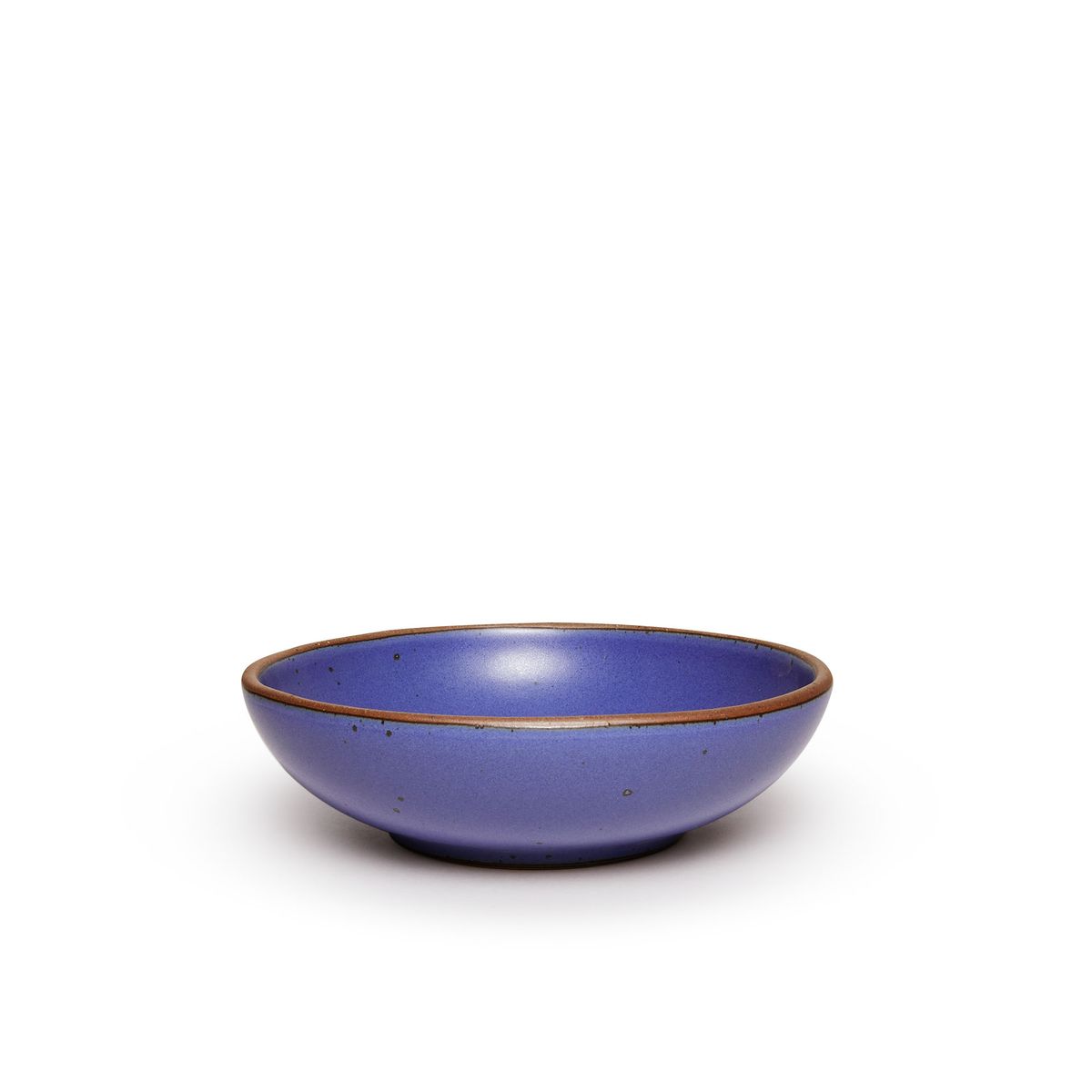 A dinner-sized shallow ceramic bowl in a true cool blue color featuring iron speckles and an unglazed rim