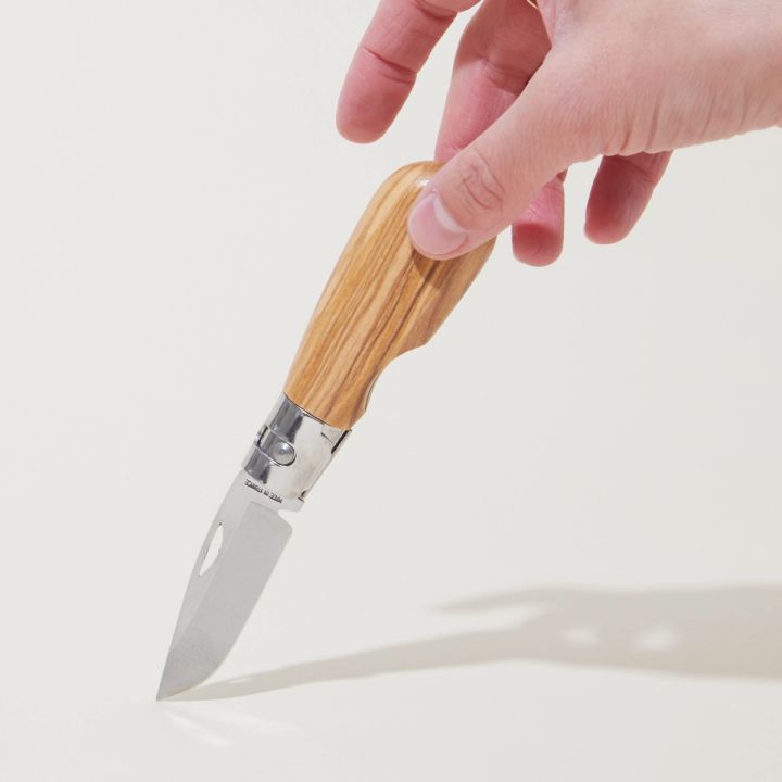 Hand holding an open pocket knife with an olivewood handle