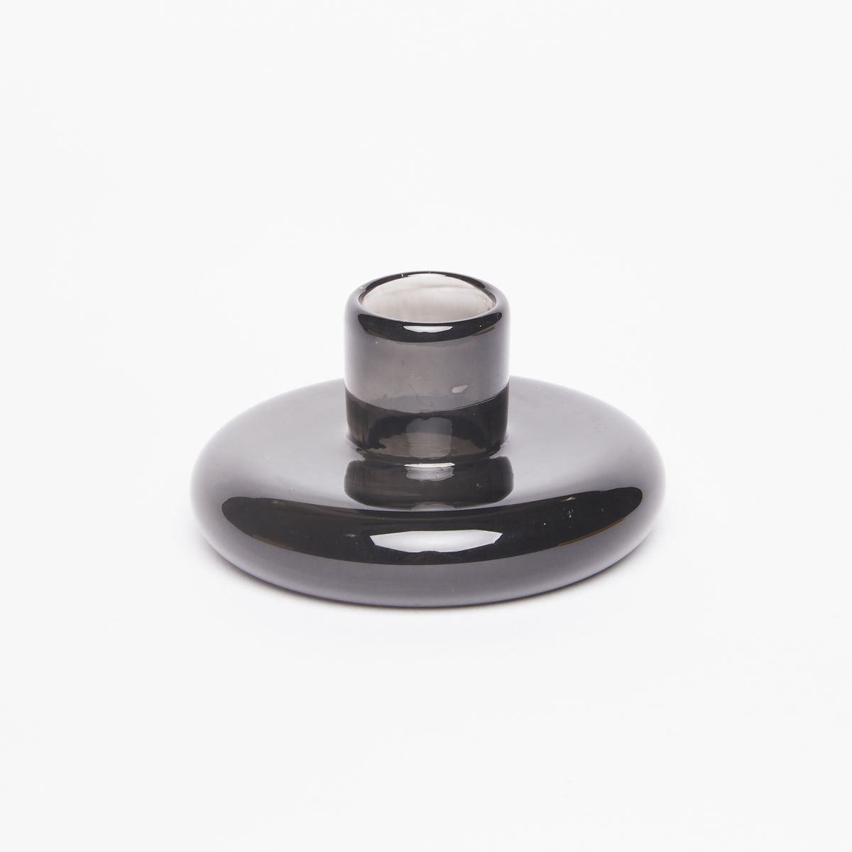 Candle holder made of a clear dark grey glass disc-like base with a small cup for the candle at center