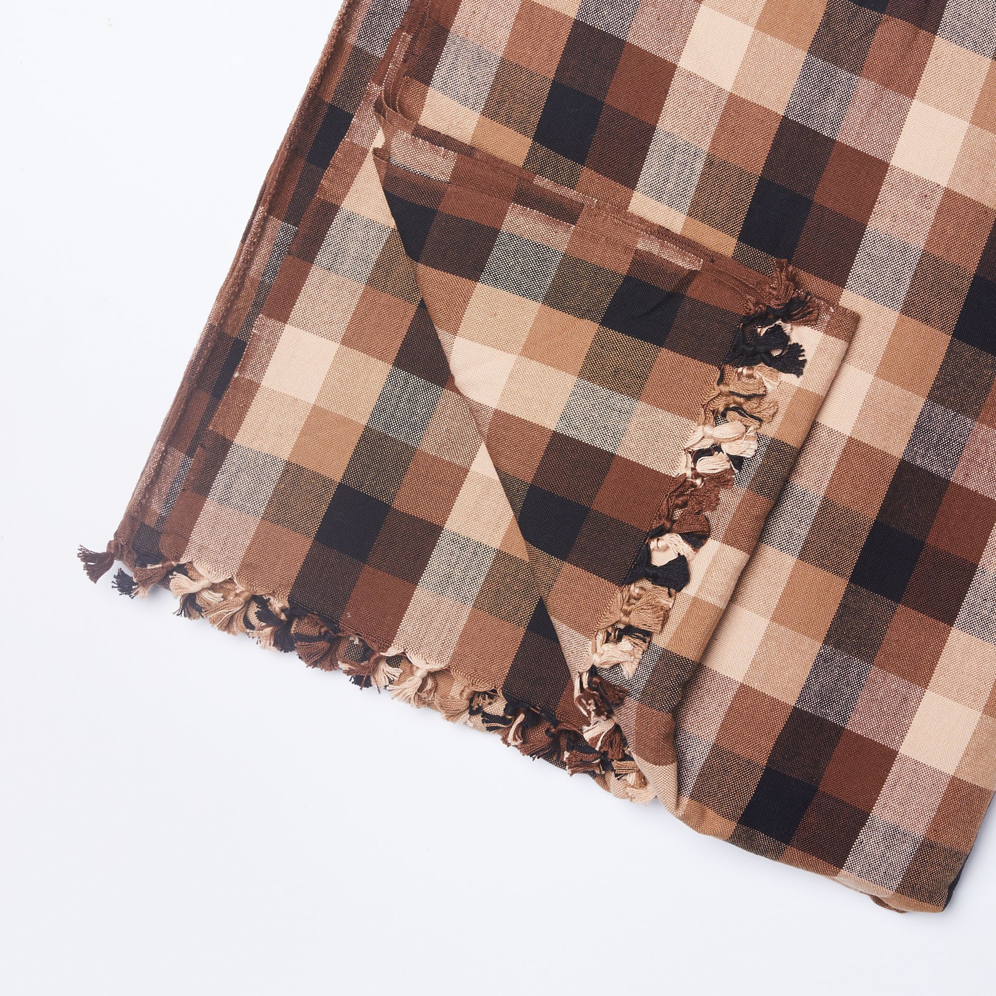 A folded gingham cotton tablecloth in shades of brown with one corner pulled back