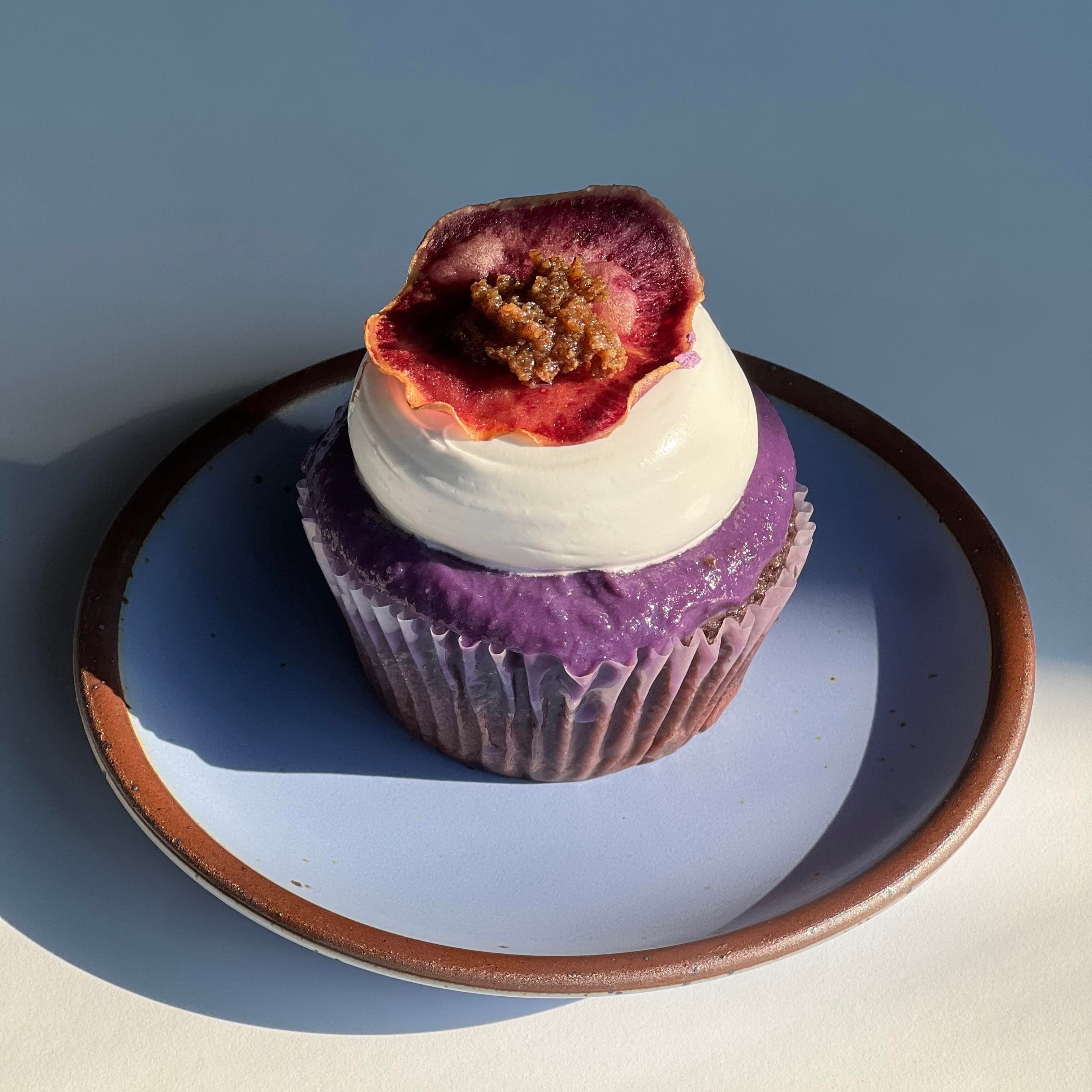 An Ube Tres Leches Cupcake sits on a periwinkle ceramic plate with an unglazed rim.