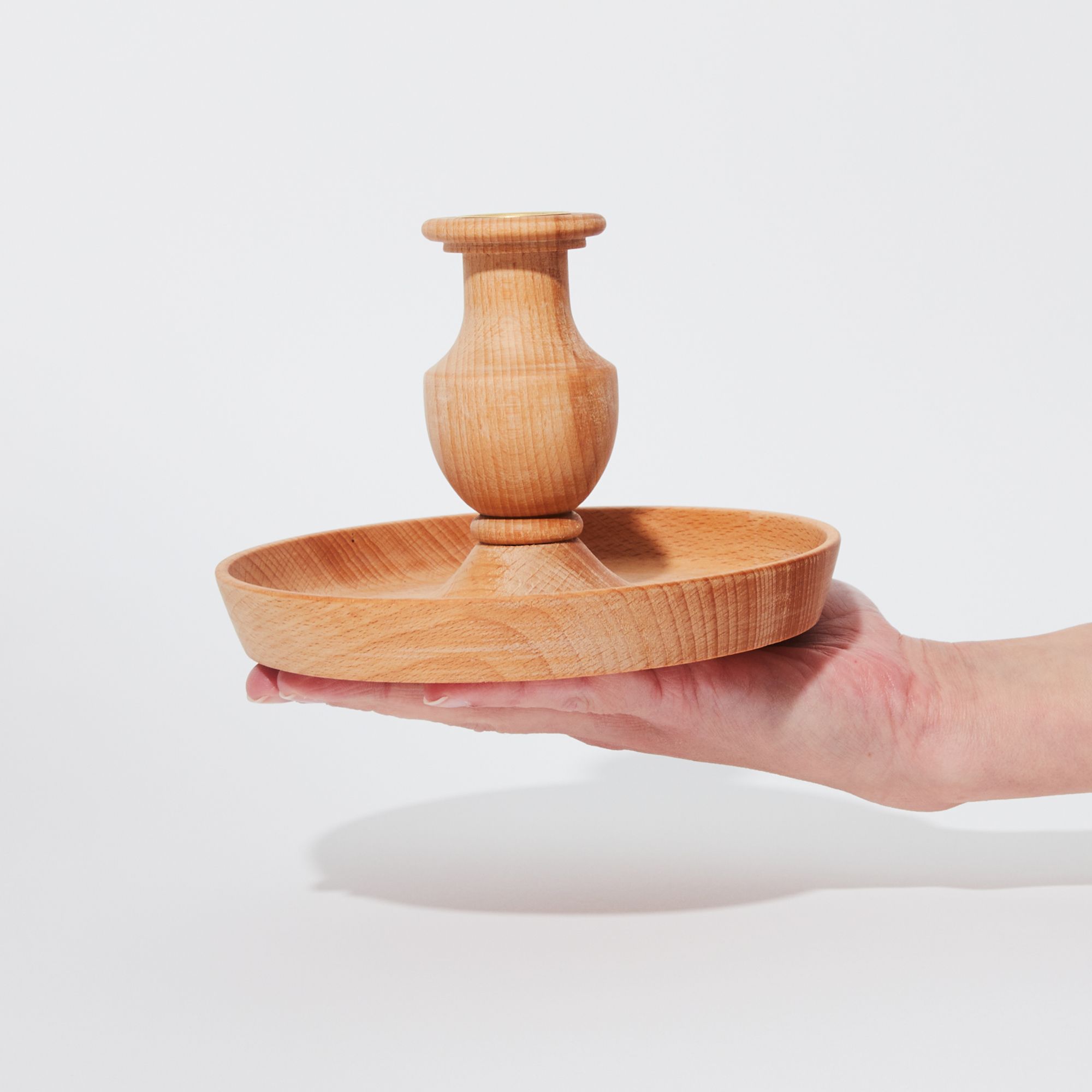 Hand holding wooden circular candle holder with tray 