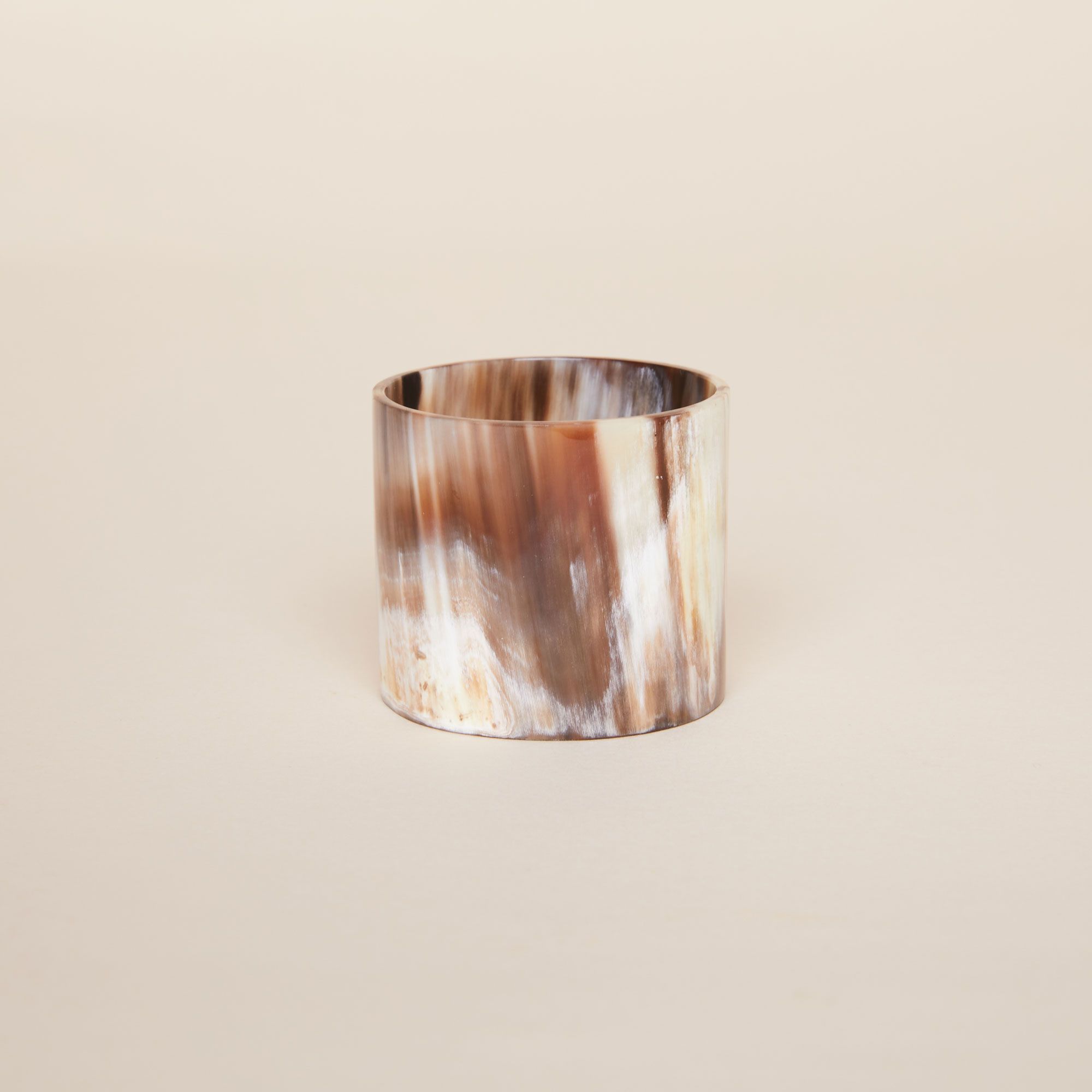 One cylindrical napkin ring in shiny browns, yellows and whites
