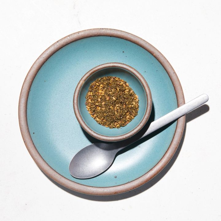 Bitty bowl full of a green spice mix on top of a plate next to a spoon