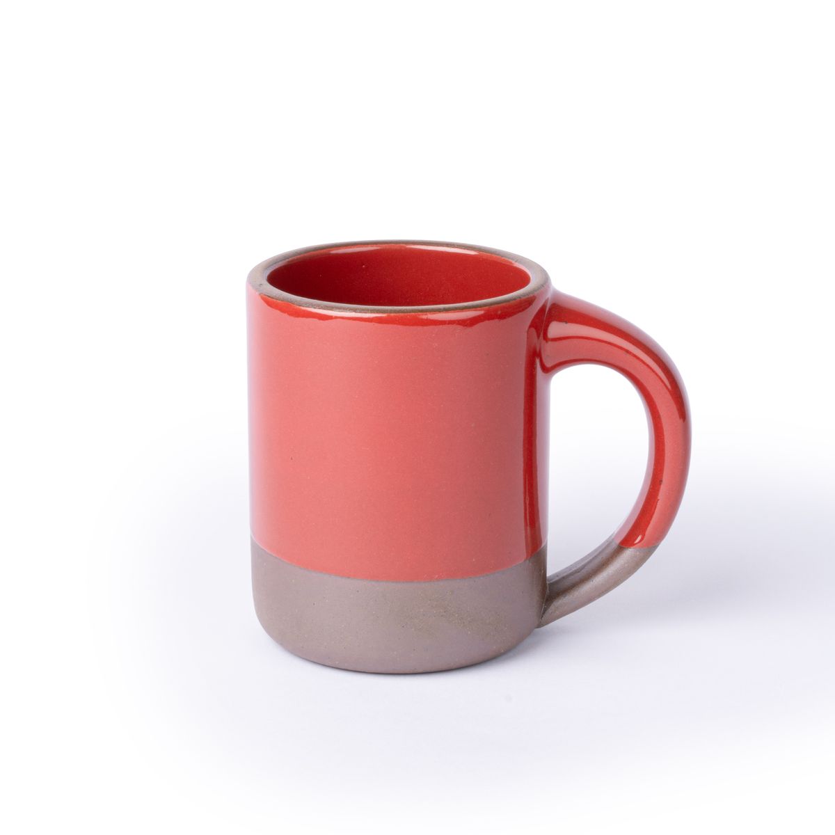 A big sized ceramic mug with handle in a glossy red color featuring iron speckles and unglazed rim and bottom base.
