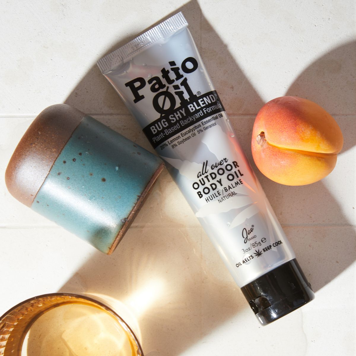 turquoise pottery cup, silver squeeze tube with black lettering, ceramic apricot laying on a table