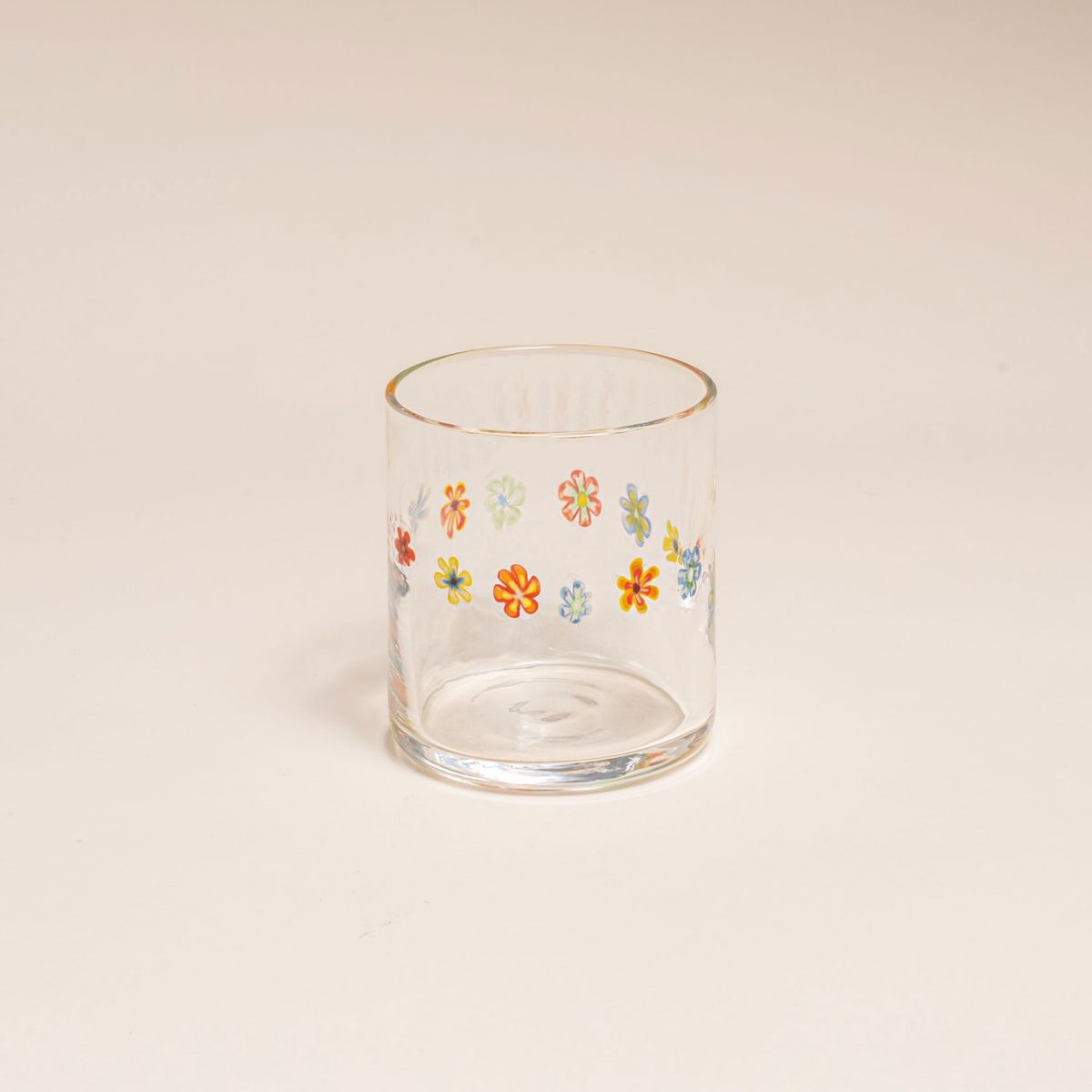 Clear glass with a ring of multicolored little flowers on a cream background.