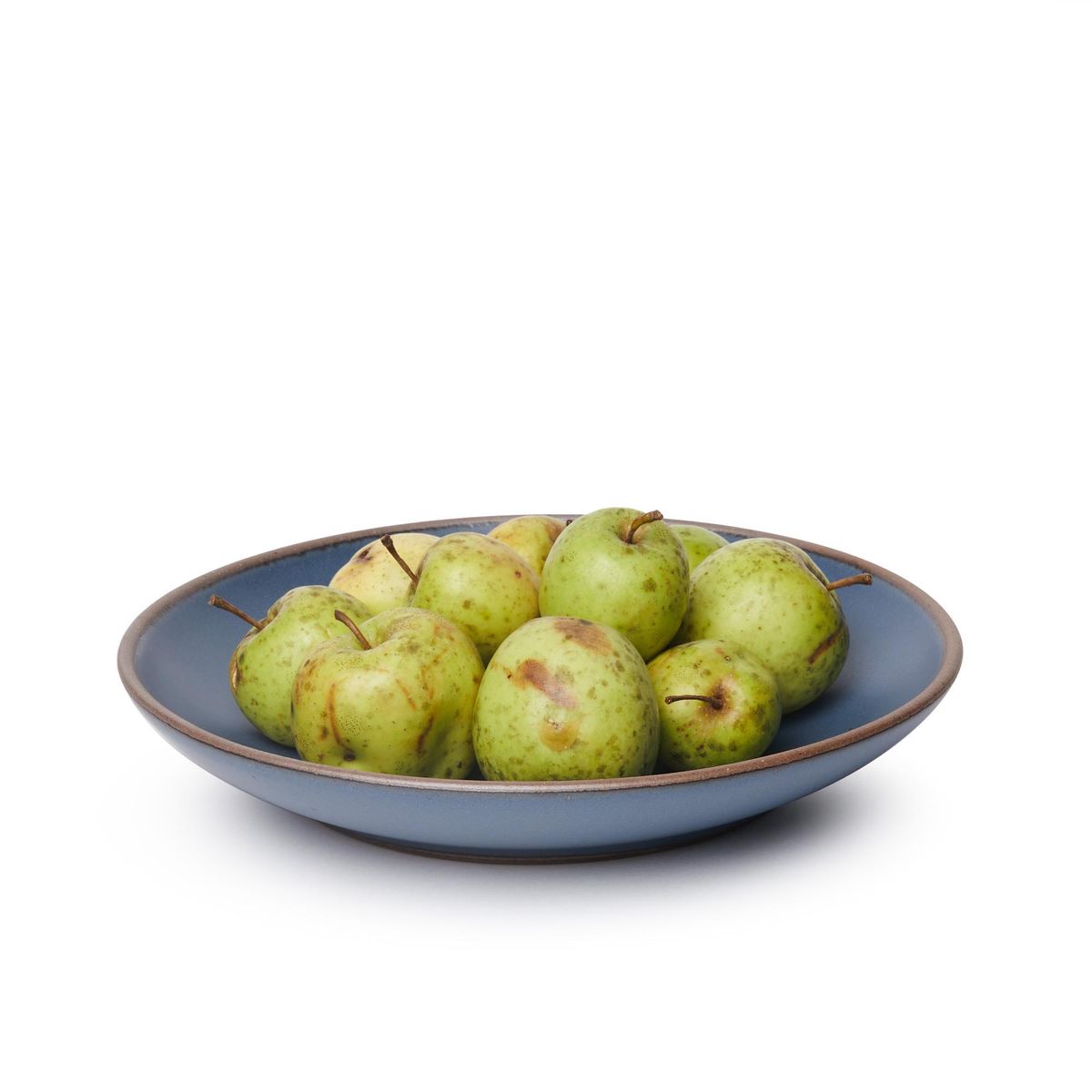 Pears on a large ceramic plate with a curved bowl edge in a toned-down navy color featuring iron speckles and an unglazed rim.