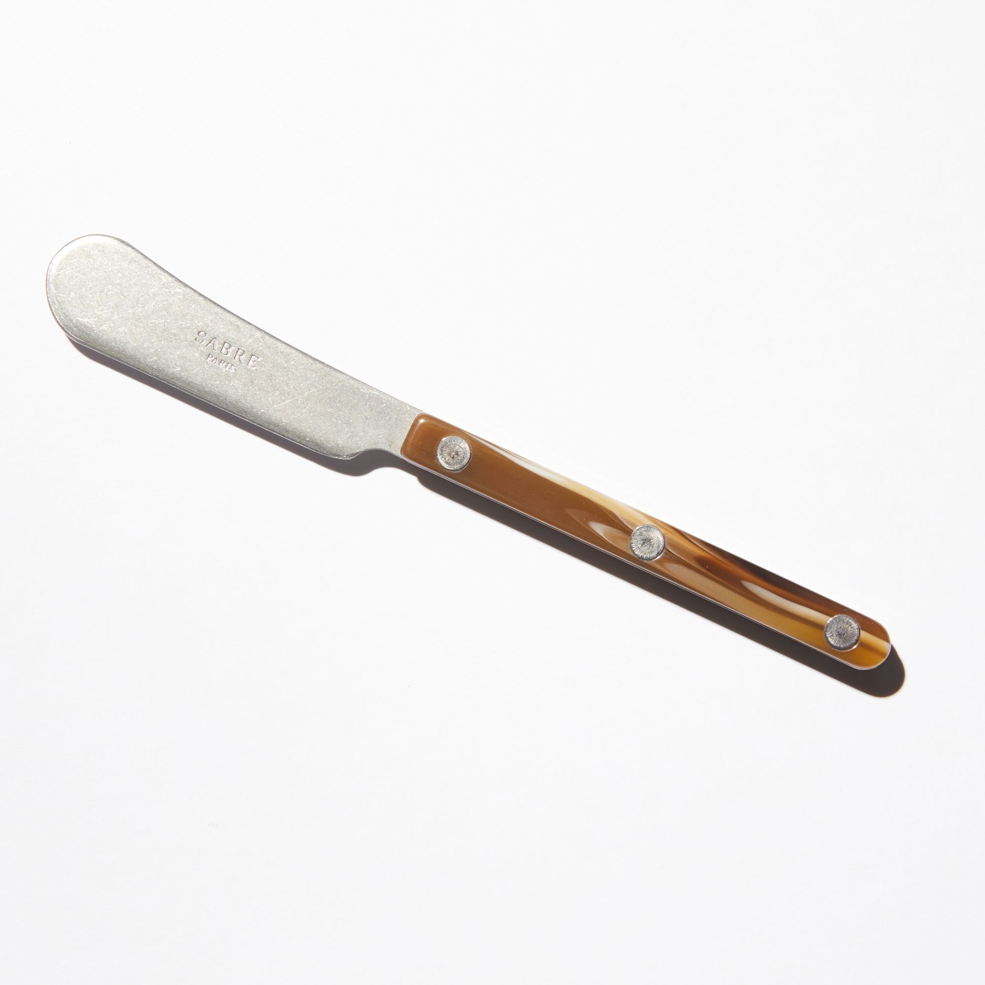 A cheese knife with a short blade that gets wider at the end. Has a matte acrylic handle.