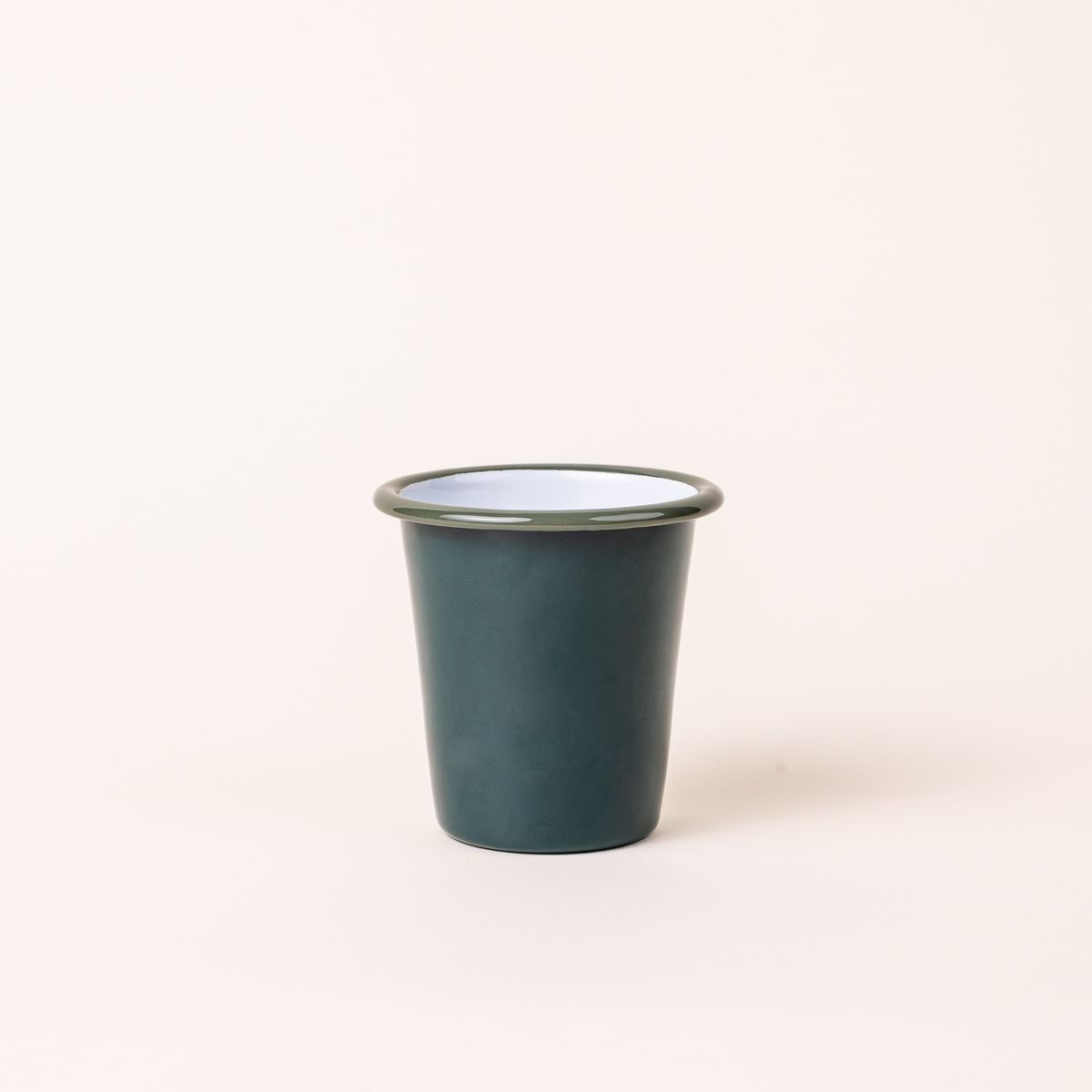 A short enamel cup with dark green teal exterior and white interior