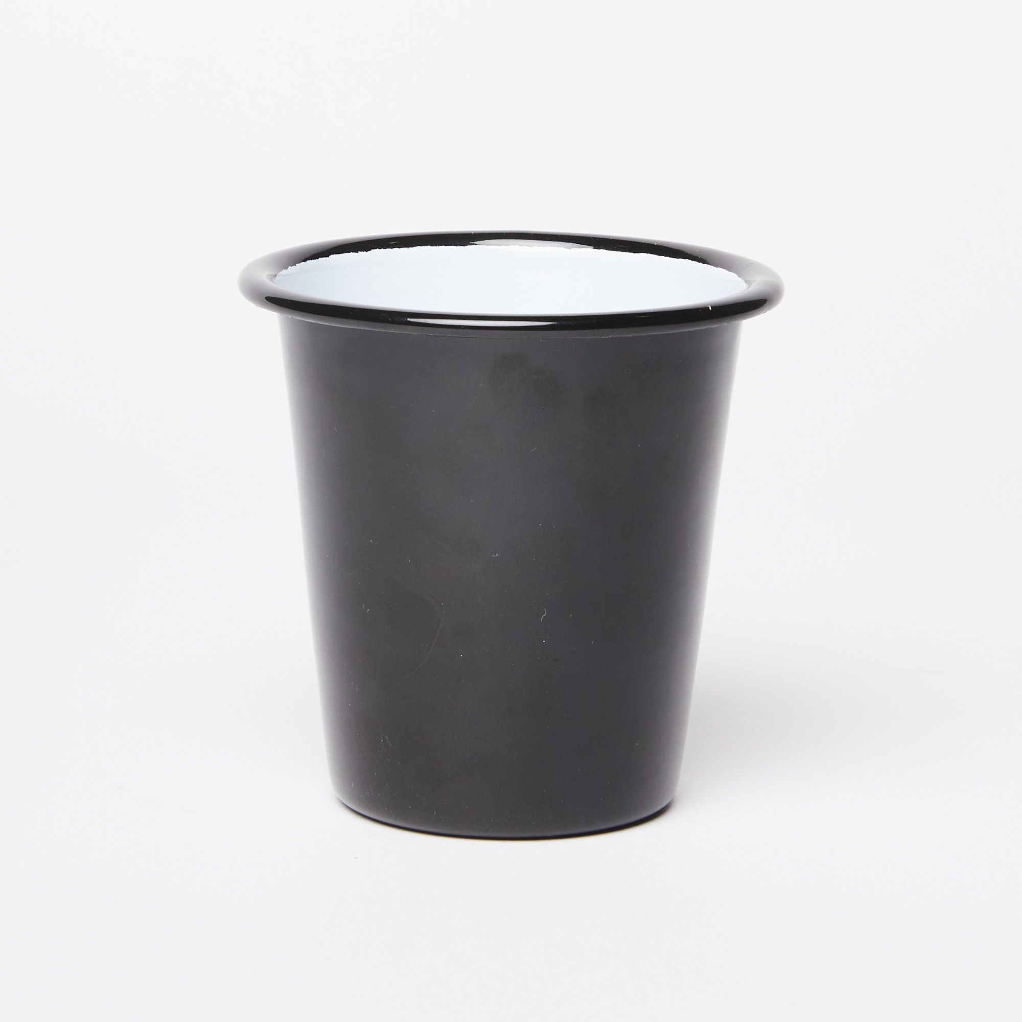 A short enamel cup with black exterior and white interior