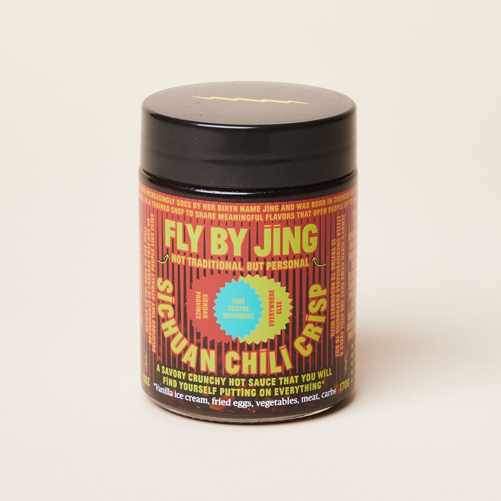 Black jar with red, yellow and blue label that identifies the product as Sichuan Chili Crisp made by Fly By Jing