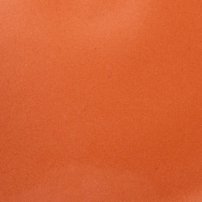 A closeup of a ceramic plate in a bold orange color