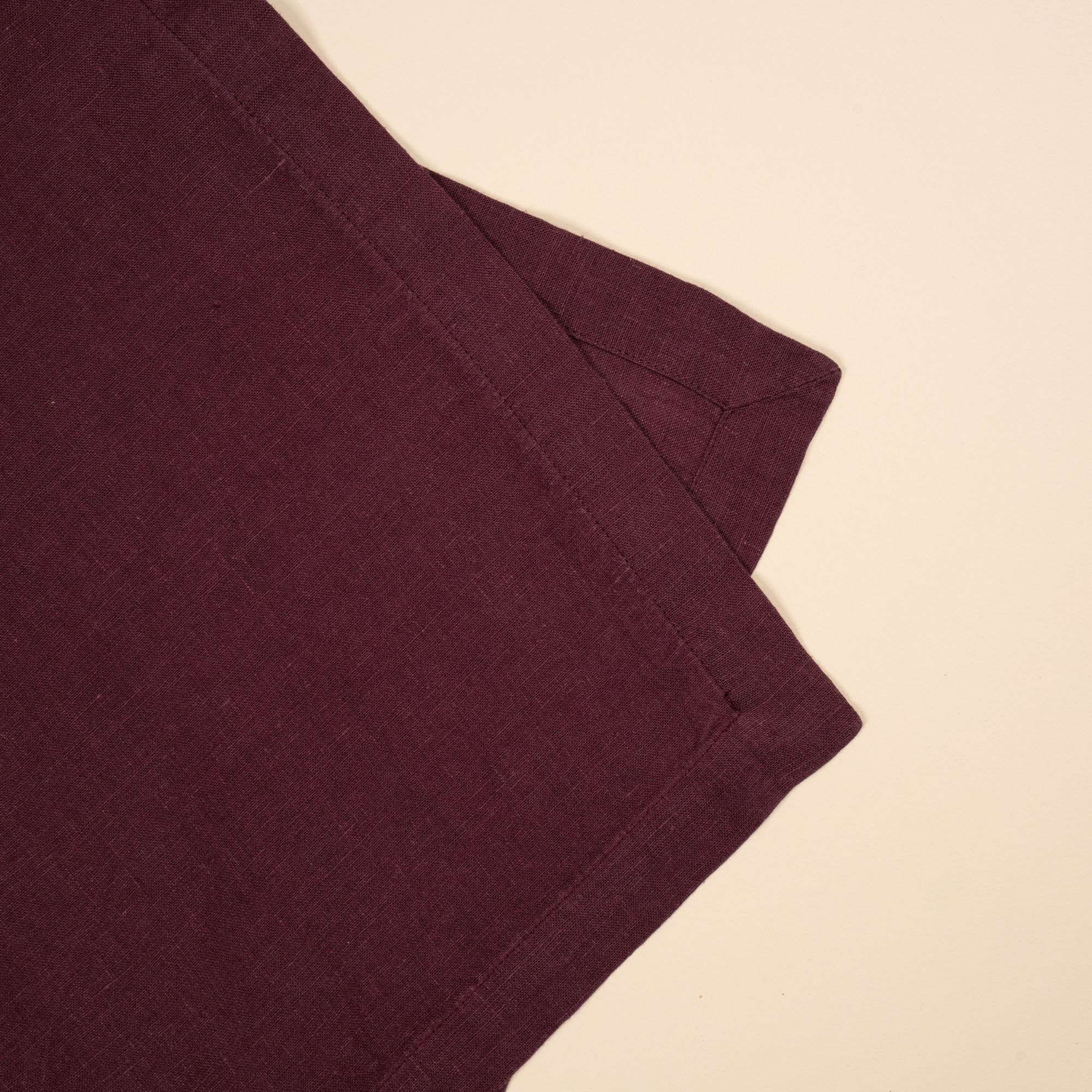 A closeup of a folded linen table runner in a deep purple color