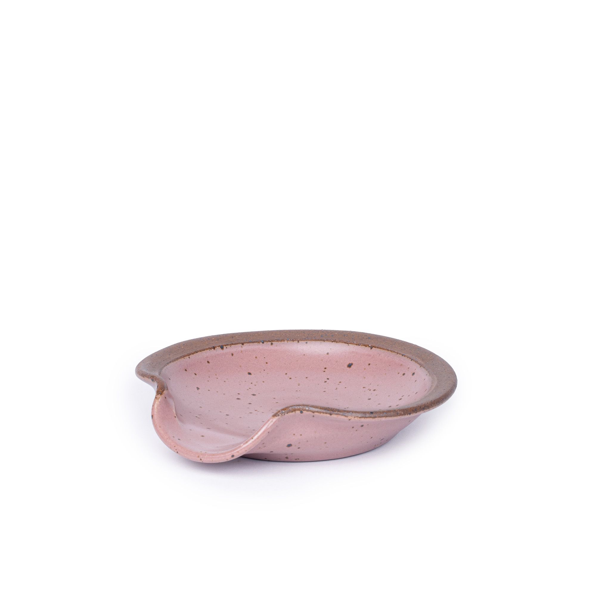 A circular ceramic spoon rest in a dusty mauve pink color featuring iron speckles and unglazed ridge rim
