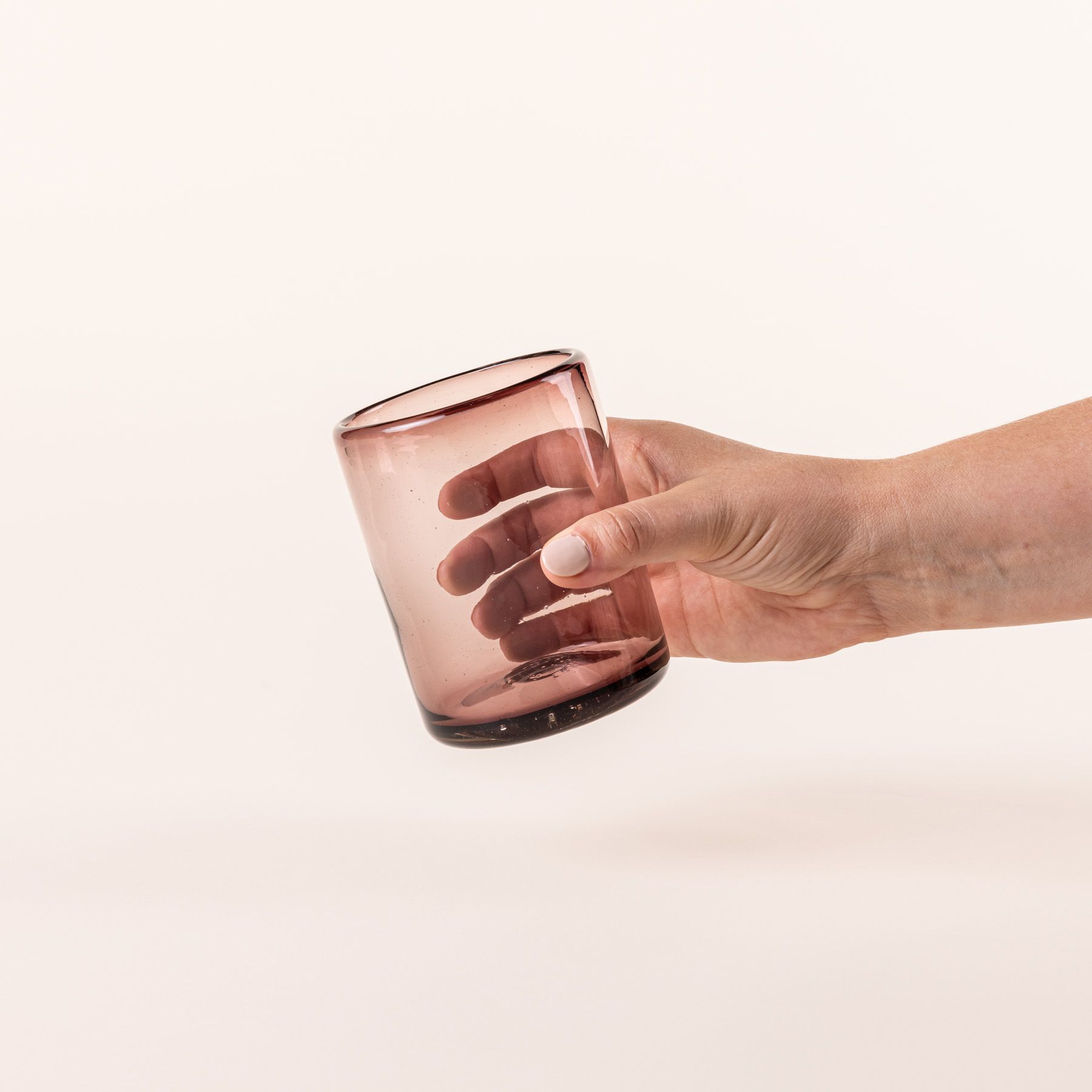 A hand a light plum short drinking glass