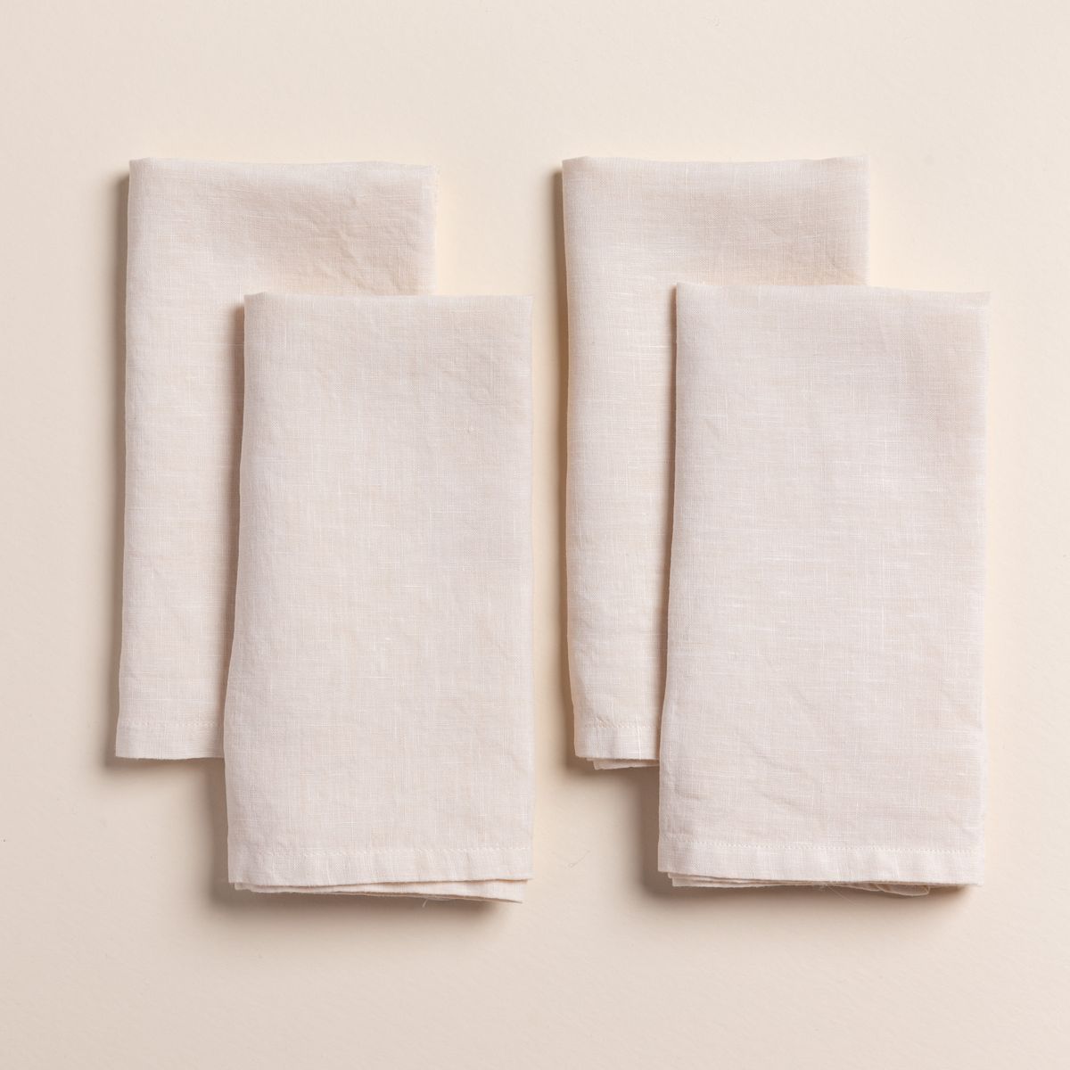 4 folded linen napkins in a cream color