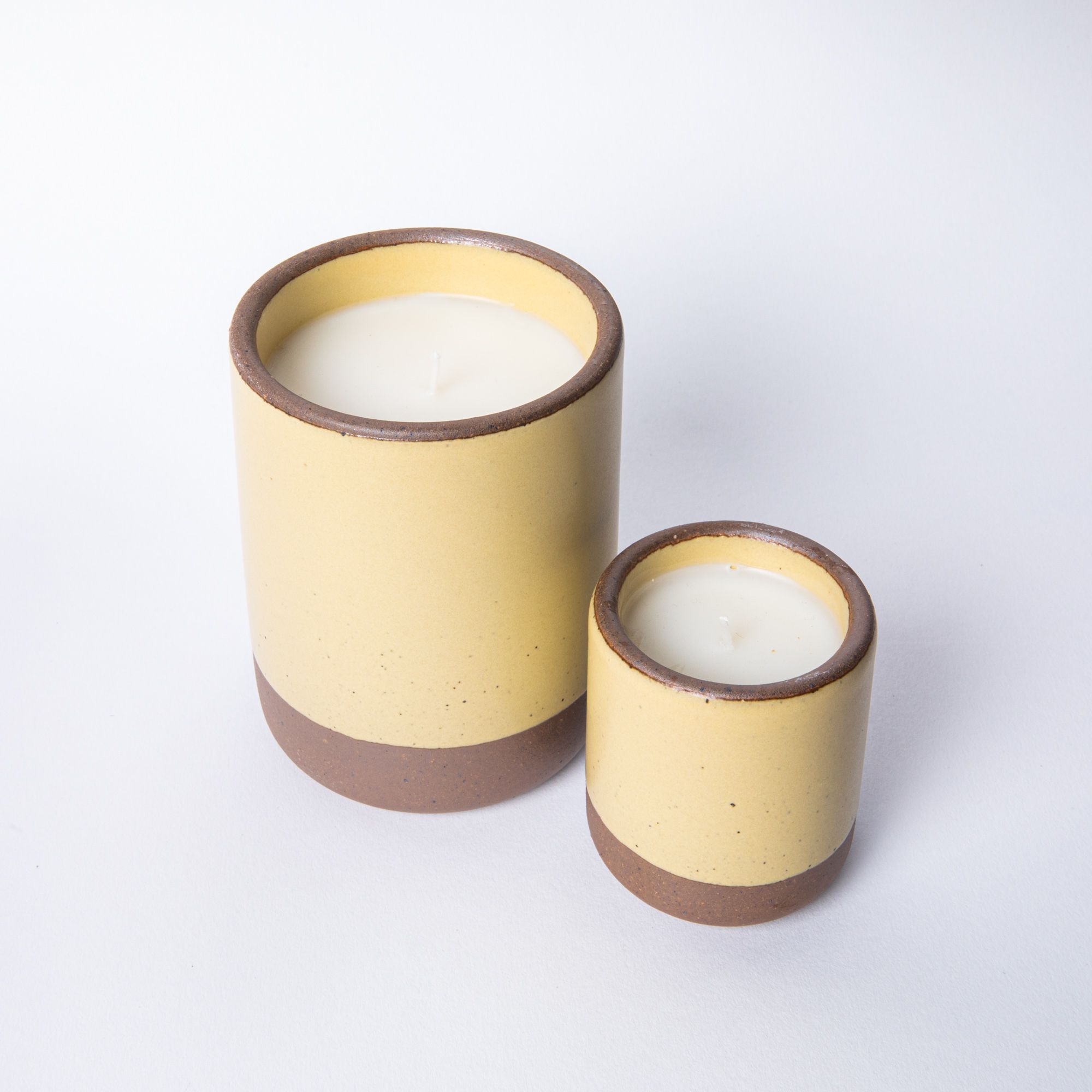 A large and small ceramic vessel in soft butter yellow color with candle inside