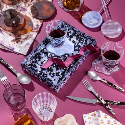 An artful arrangement of items with fun patterns and textures including glassware, an acrylic tray, sophisticated flatware and more.
