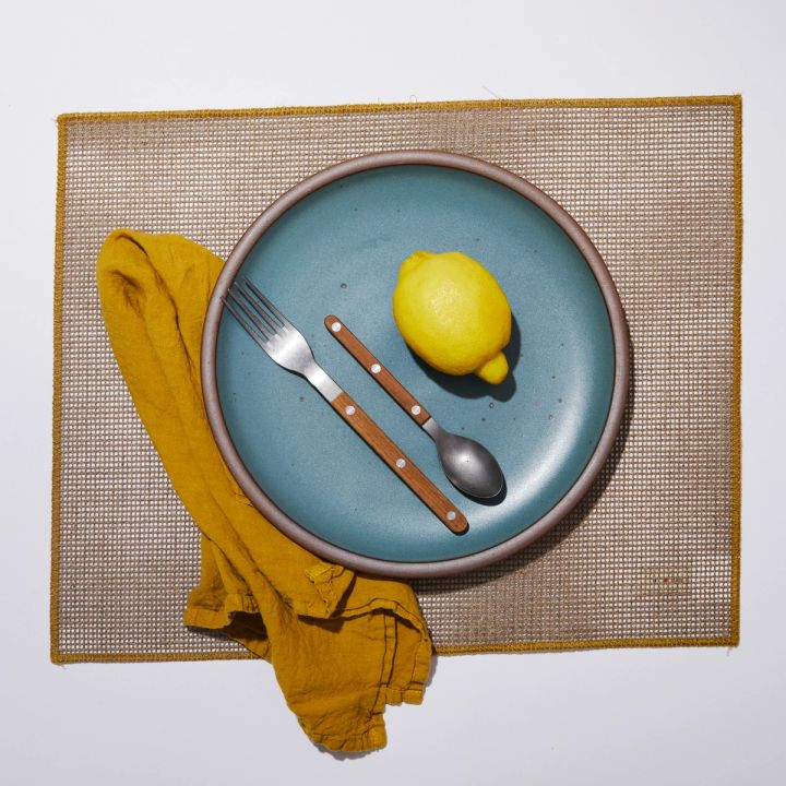 placemat with yellow linen towel, plate, silverware and lemon on top