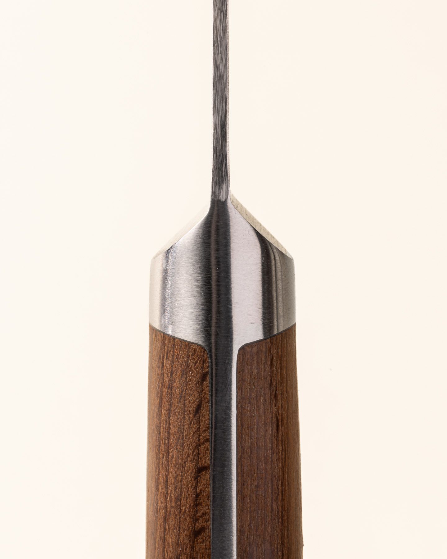 A close up of where the wooden handle meets the steel blade of a paring knife