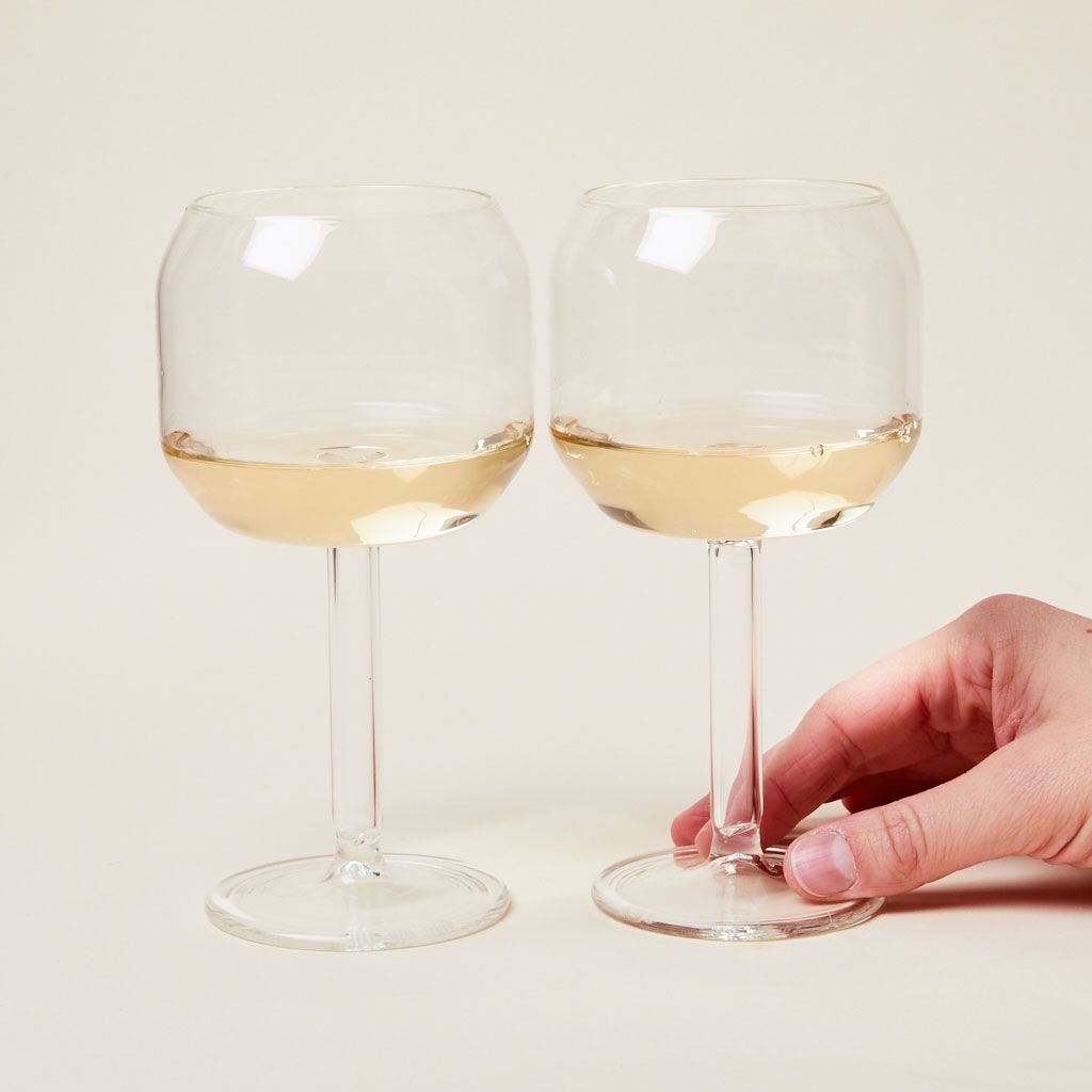 A hand touches one of two Velasca calices: stemmed wine glasses with large, tall bowls