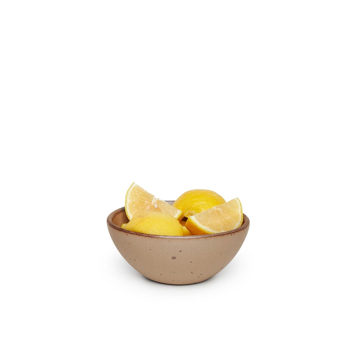A small dessert sized rounded ceramic bowl in a warm pale brown color featuring iron speckles and an unglazed rim, filled with lemon wedges