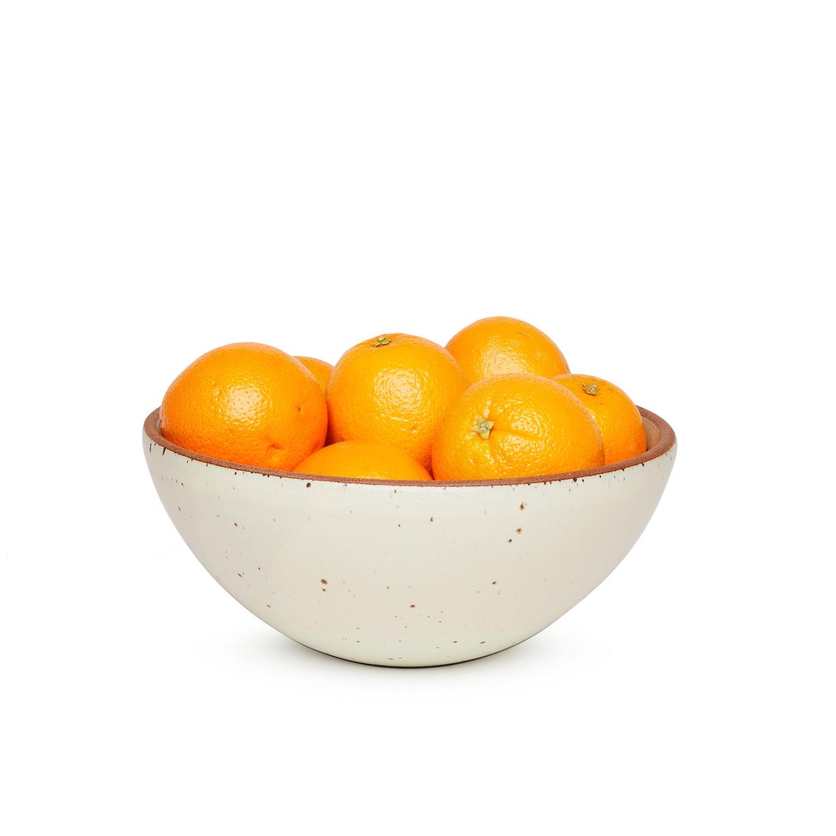 A large rounded ceramic bowl in a warm, tan-toned, off-white color featuring iron speckles and an unglazed rim, filled with oranges