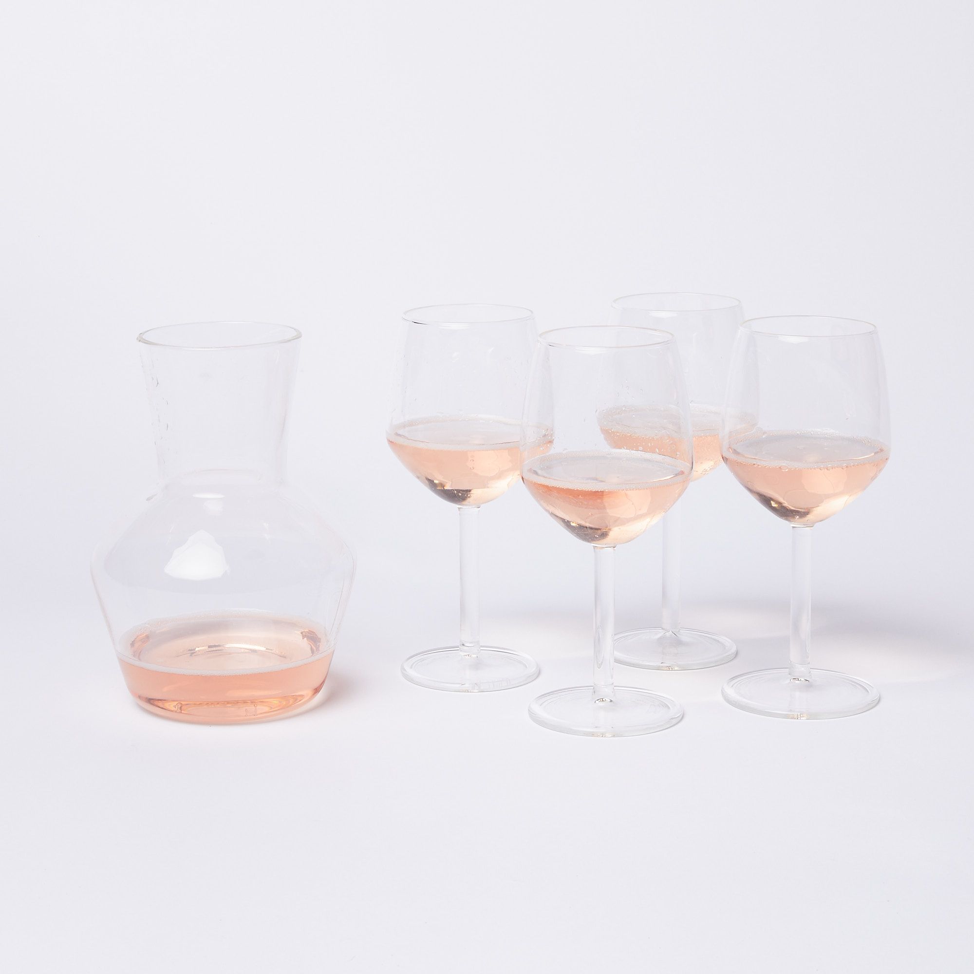4 wine glasses and a carafe with rose