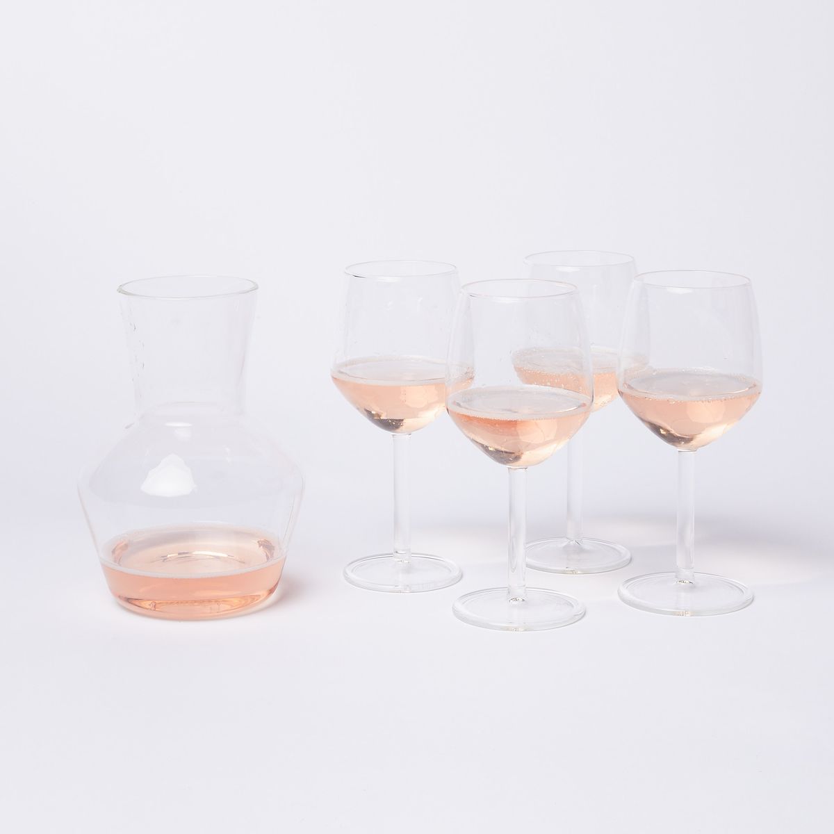 4 wine glasses and a carafe with rose