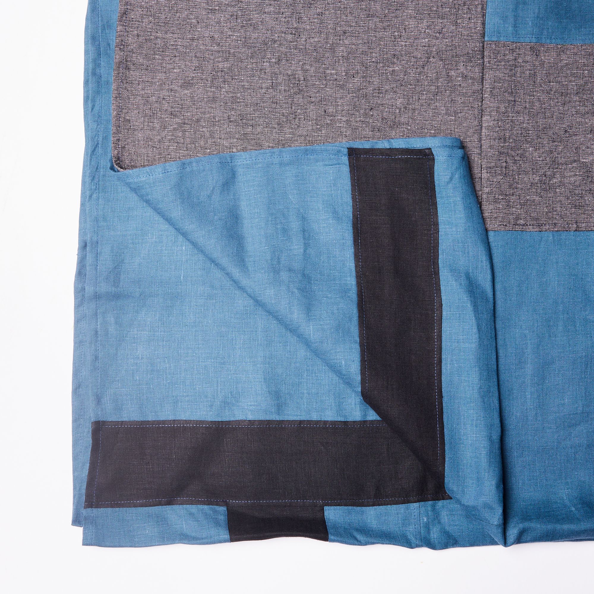 Corner of tablecloth with grey, blue, charcoal rectangular shapes