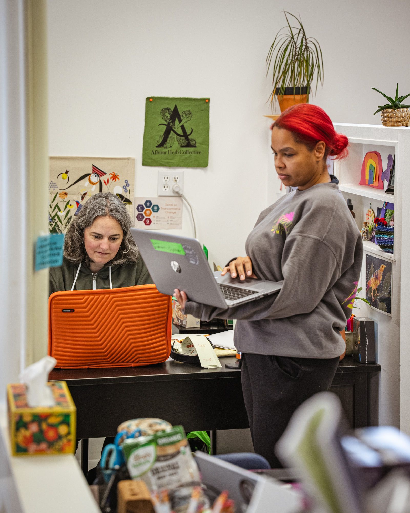 Two people work in an office setting staring at laptops