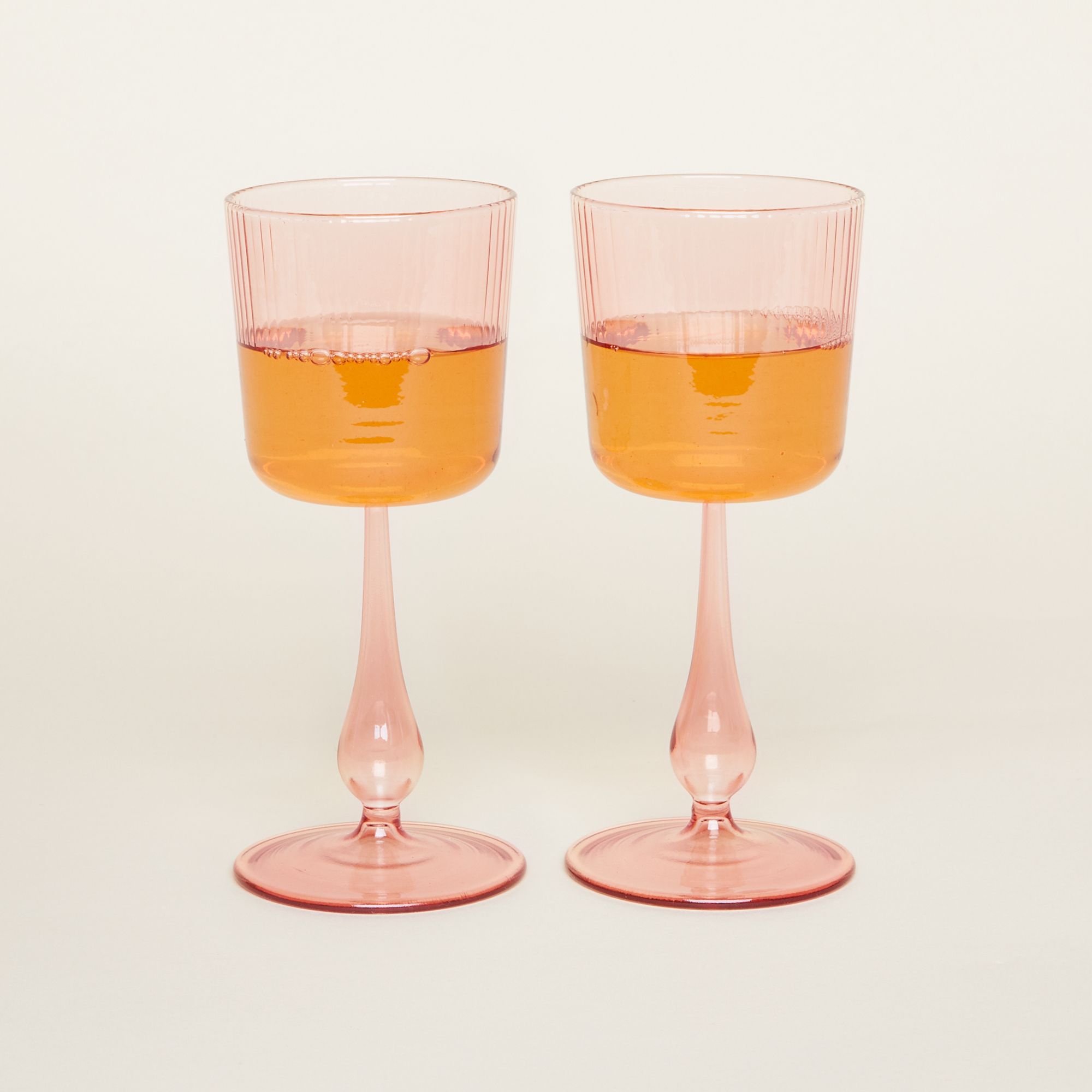 Stemmed wine glasses with grooves on the cup and stems that bow out at the end before their foot. They come in three colors: pale yellow, pale green and pale pink.