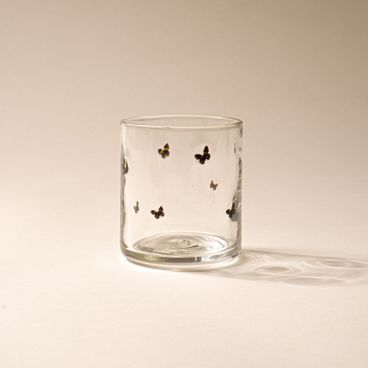 Clear glass with a ring of butterflies on a cream background.