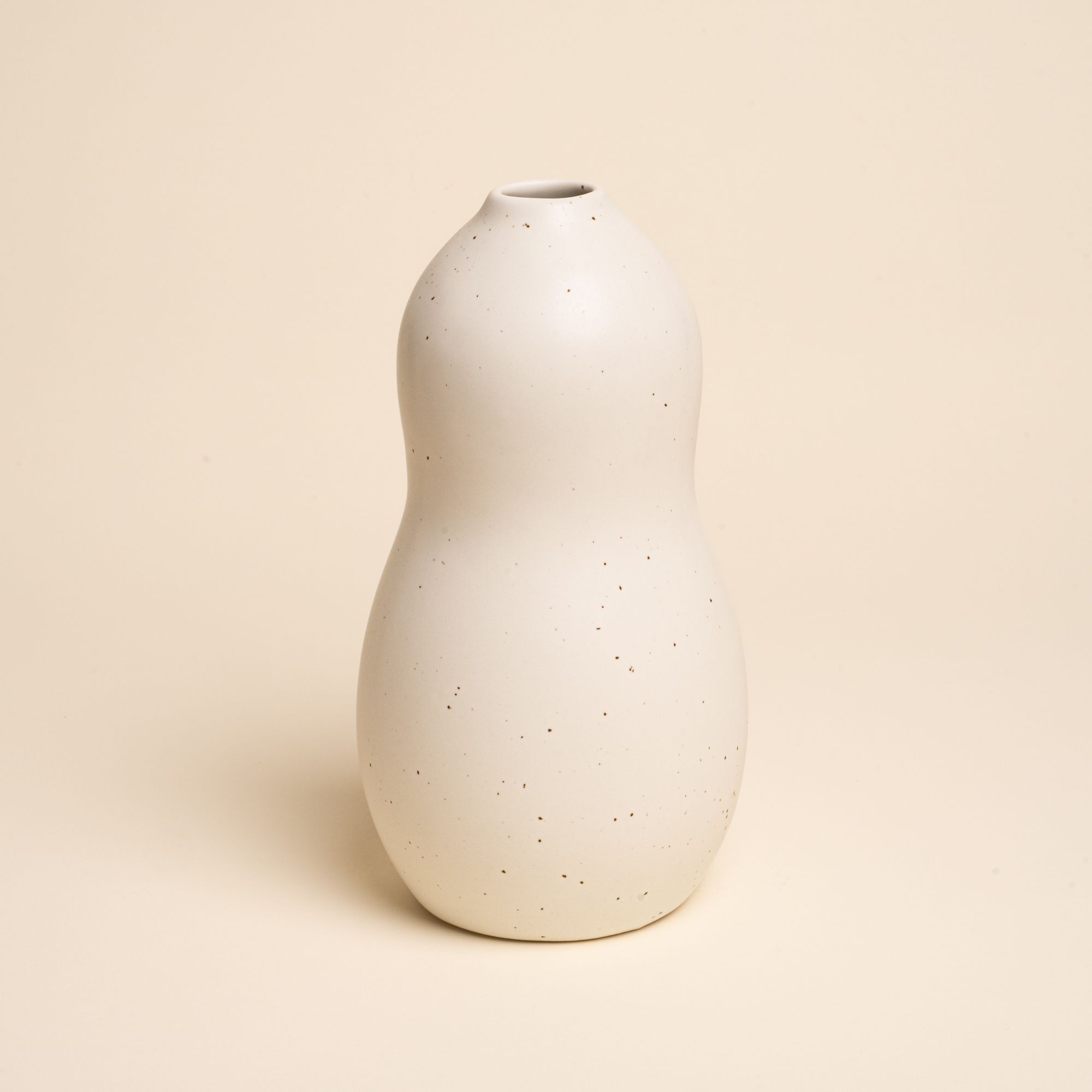 Large off-white ceramic vase with a curvy shape and subtle speckles, set against a soft beige background.