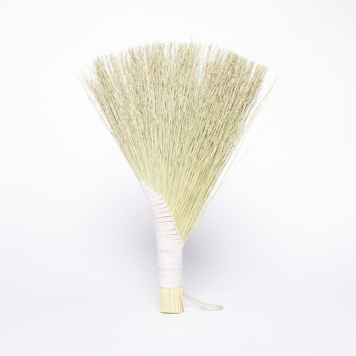 A hand broom made of sorghum that is tied at the handle and fans out at the head