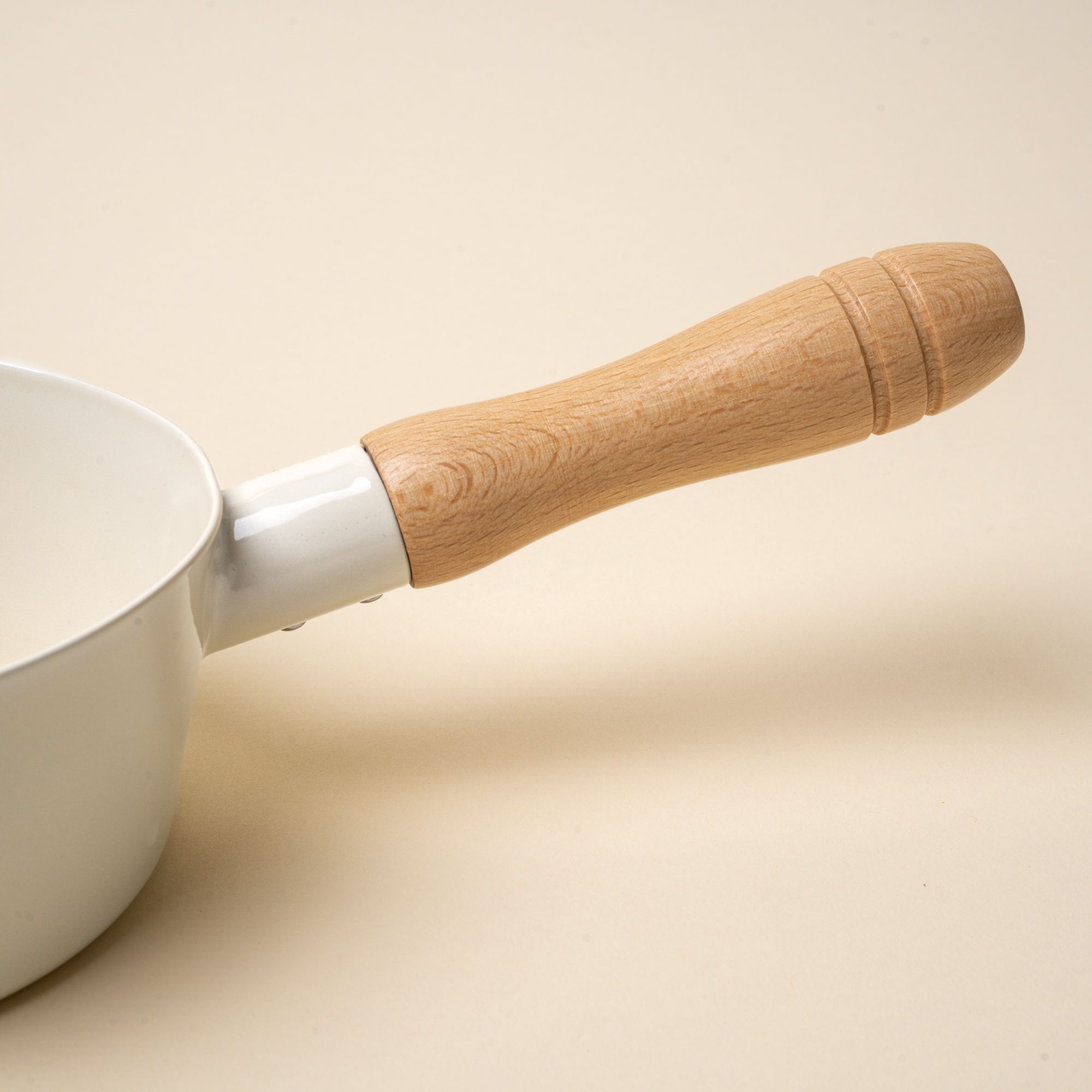 A closeup of a wooden handle on an enamel pot