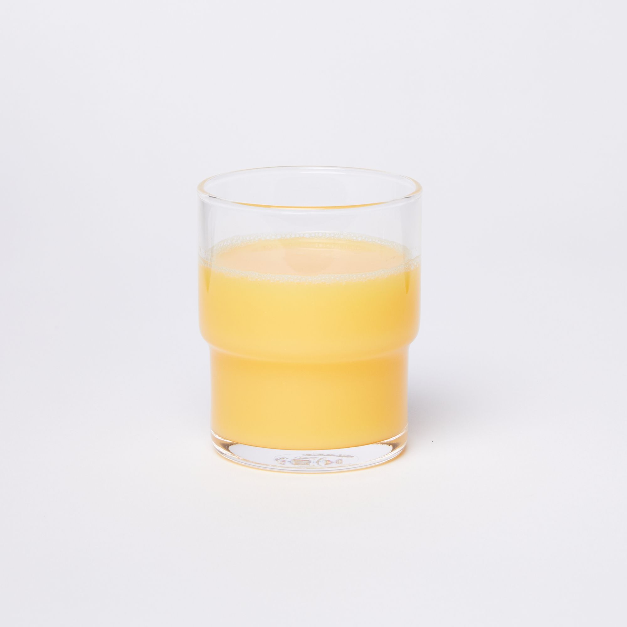 Clear cylindrical glass with a wider top half with a narrower bottom half, full of orange juice
