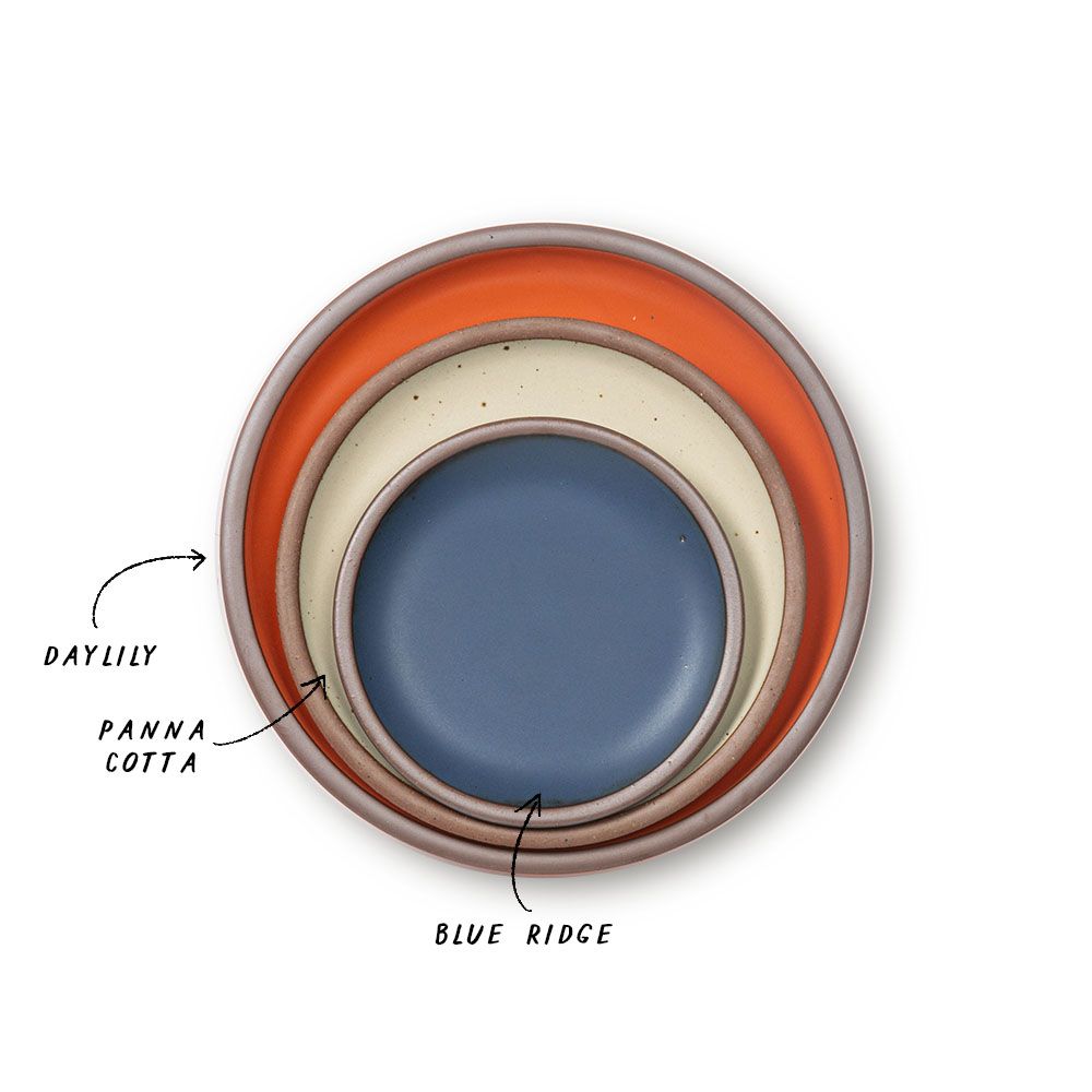 A stack of ceramic plates in a bold orange, cream, and muted navy colors.