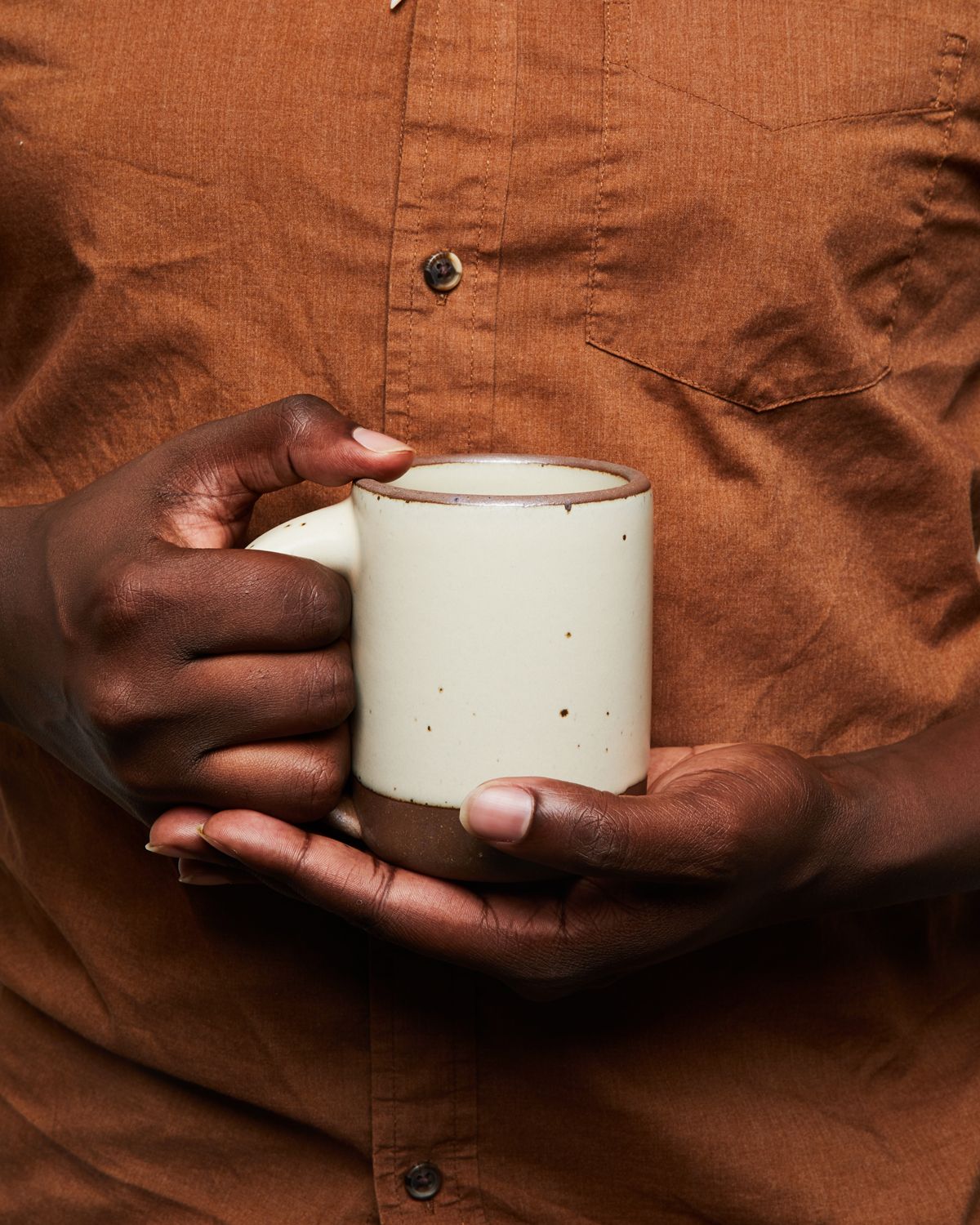 2 hands holding an East Fork Mug in a warm off-white color.