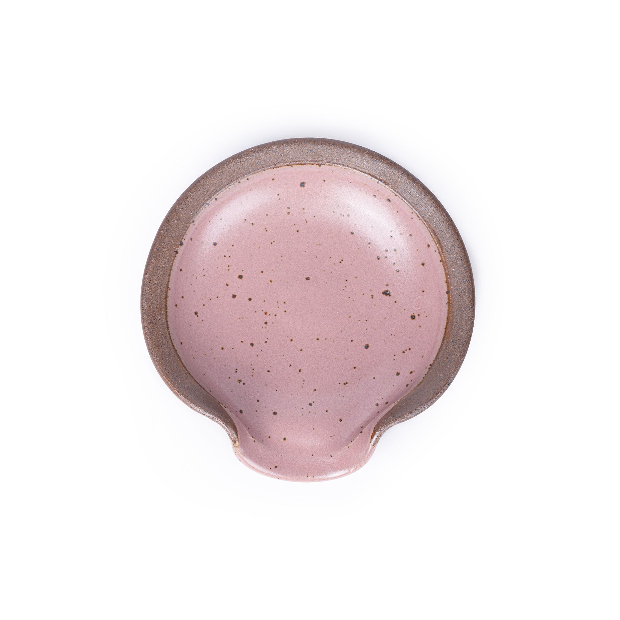 A circular ceramic spoon rest in a dusty mauve pink color featuring iron speckles and unglazed ridge rim