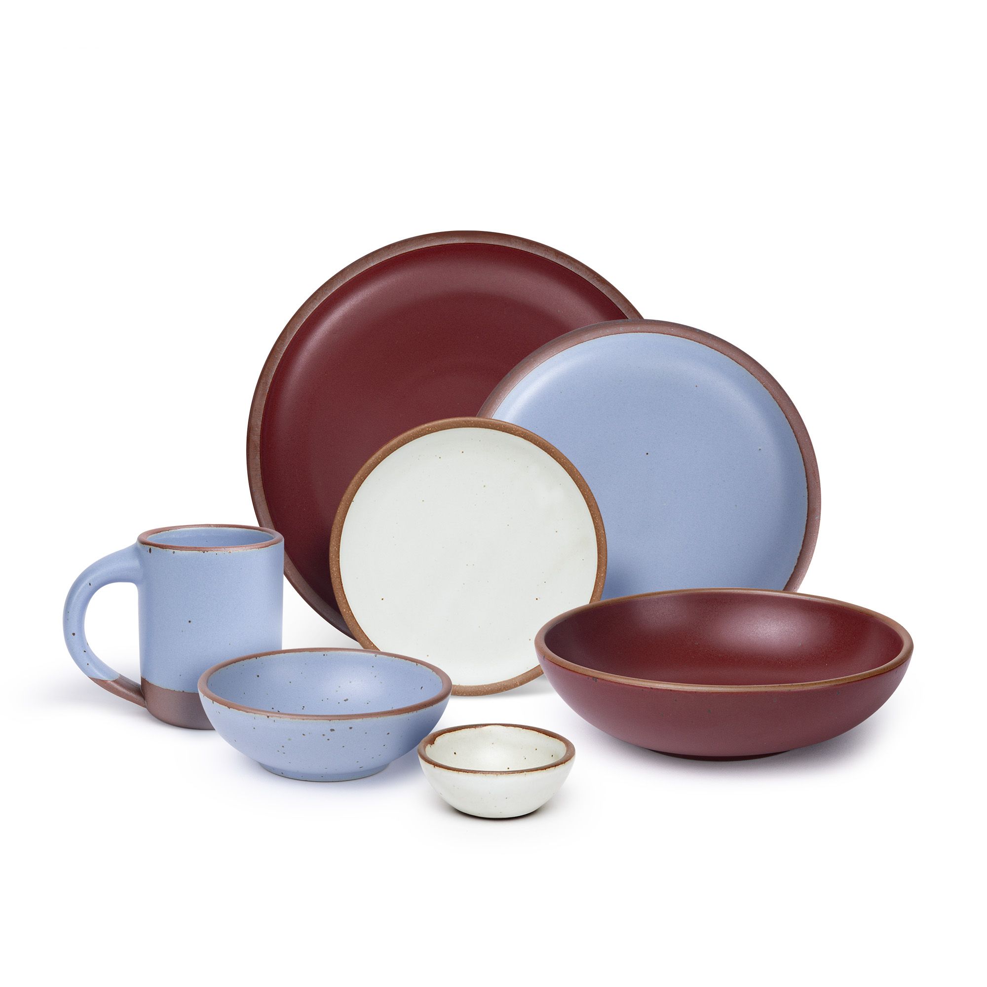 The Mug, side plate, and breakfast bowl in periwinkle, the bitty bowl and cake plate in eggshell, the everyday bowl and dinner plate in a plum color.