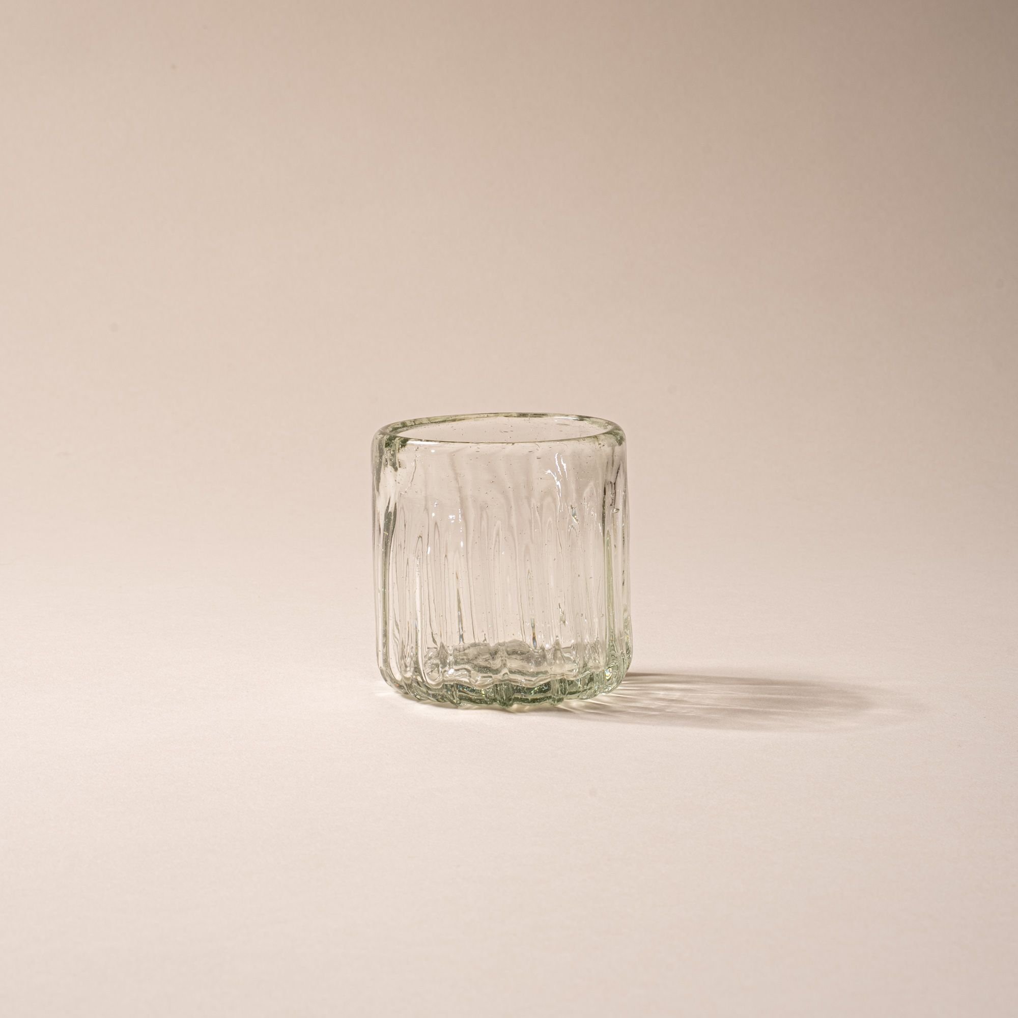 Clear textured glass tumbler with vertical ridges against a neutral background.