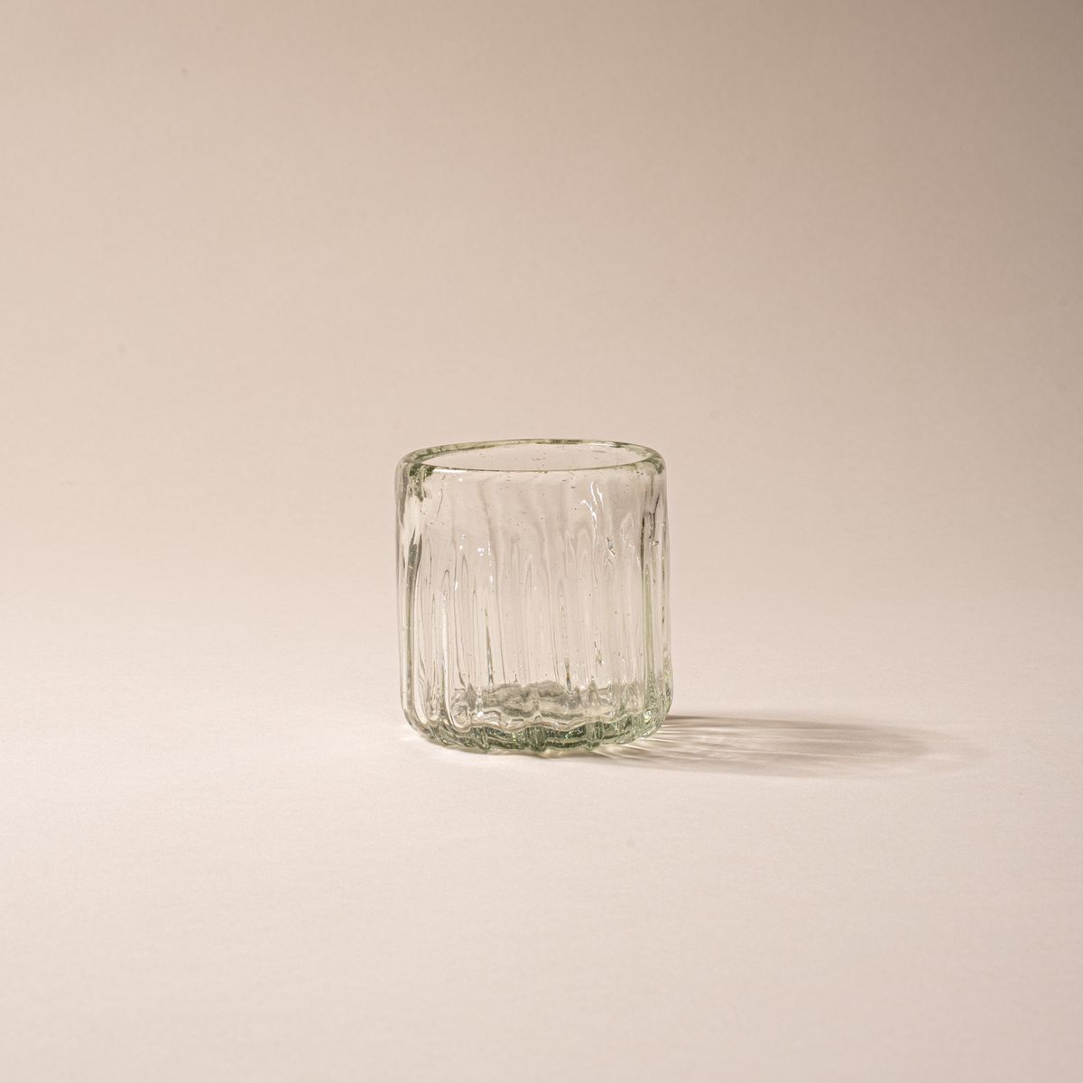Clear textured glass tumbler with vertical ridges against a neutral background.