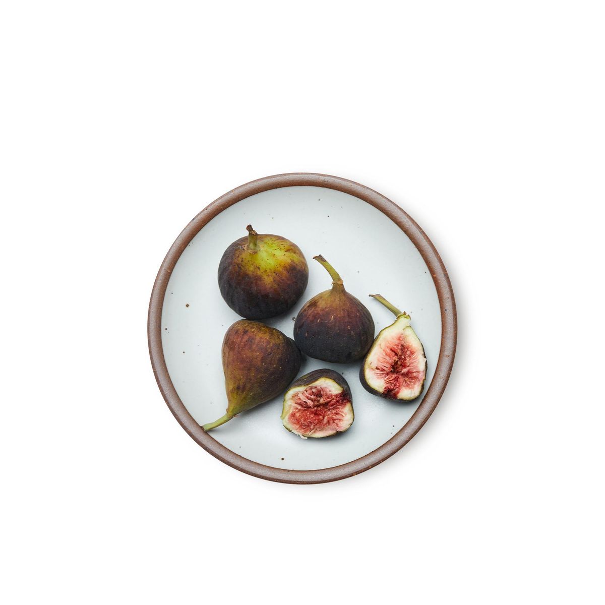 A medium sized ceramic plate in a cool white color featuring iron speckles and an unglazed rim, with figs