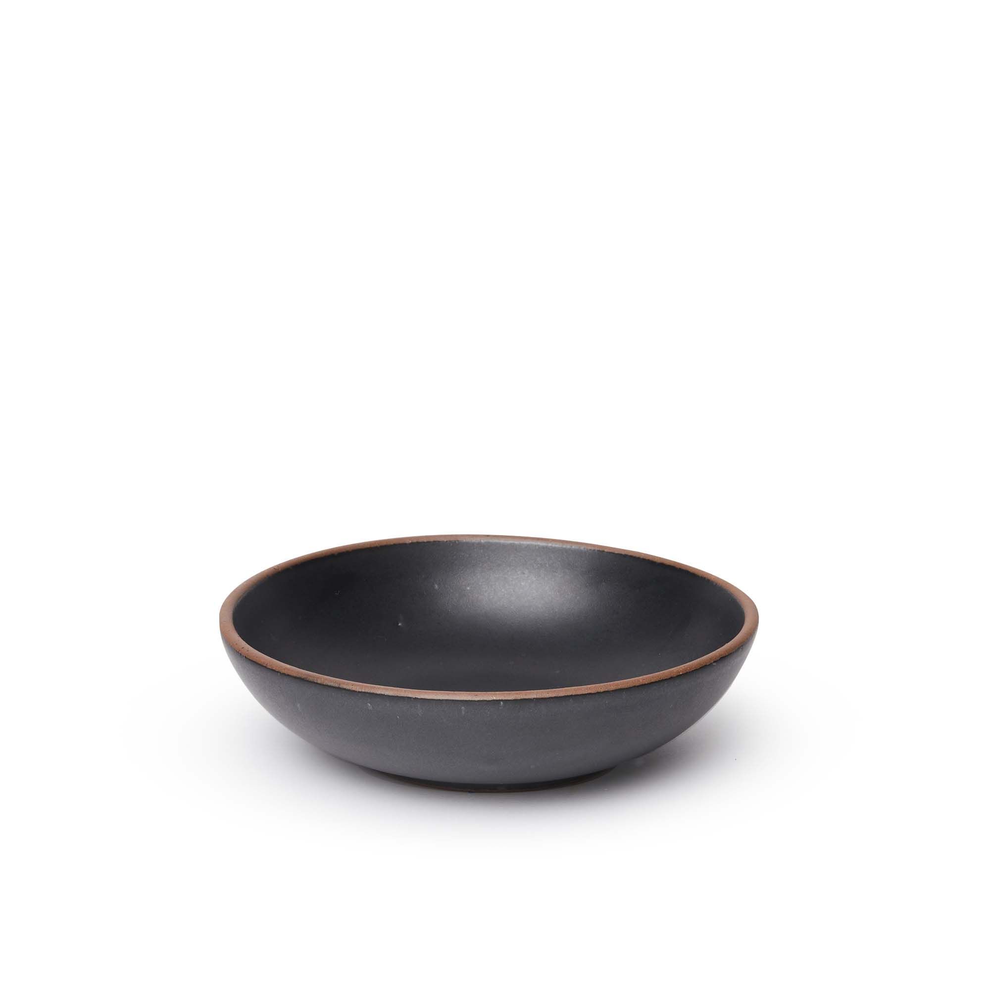 A dinner-sized shallow ceramic bowl in a graphite black color featuring iron speckles and an unglazed rim